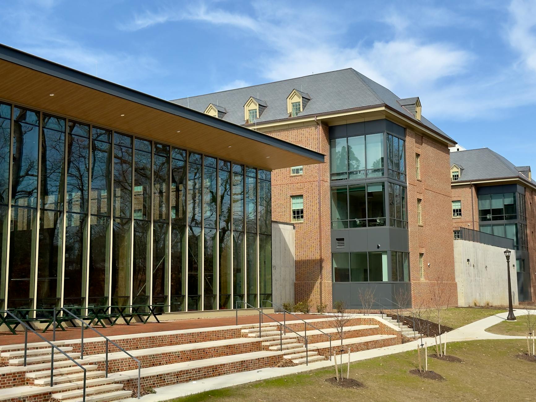 Exterior view of a modern academic building featuring large glass windows and brick architecture on a sunny day — UPI Study
