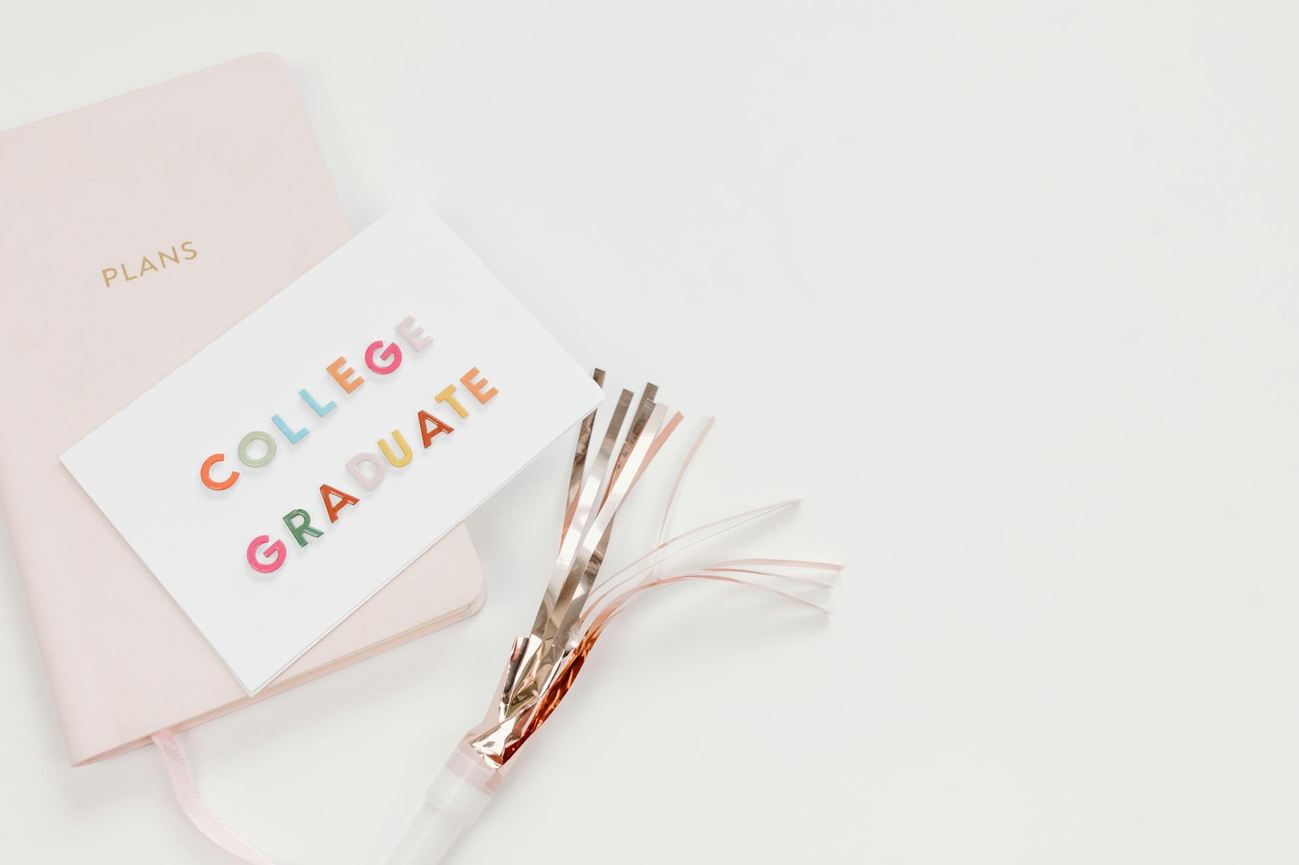 Elegant flat lay of a college graduate card with a notebook and party decor, perfect for celebration themes — UPI Study