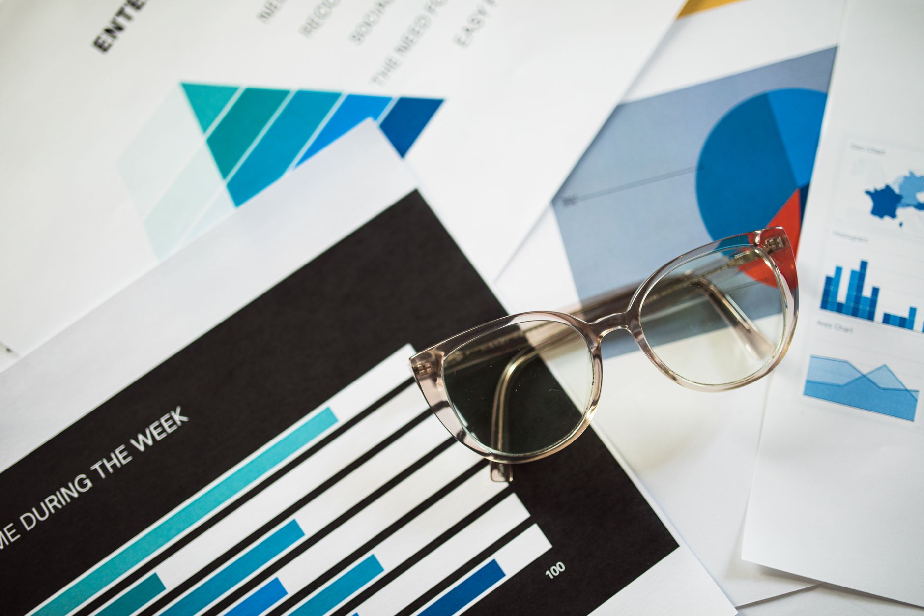 Close-up of eyeglasses resting on financial documents with various charts and graphs — UPI Study