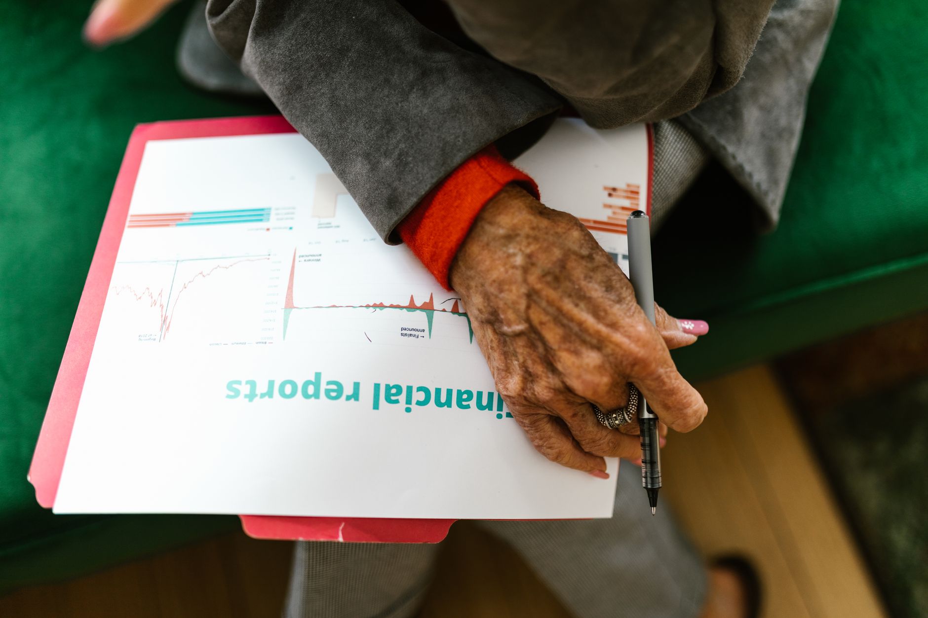 Close-up of an elderly woman holding a pen with a financial report — UPI Study