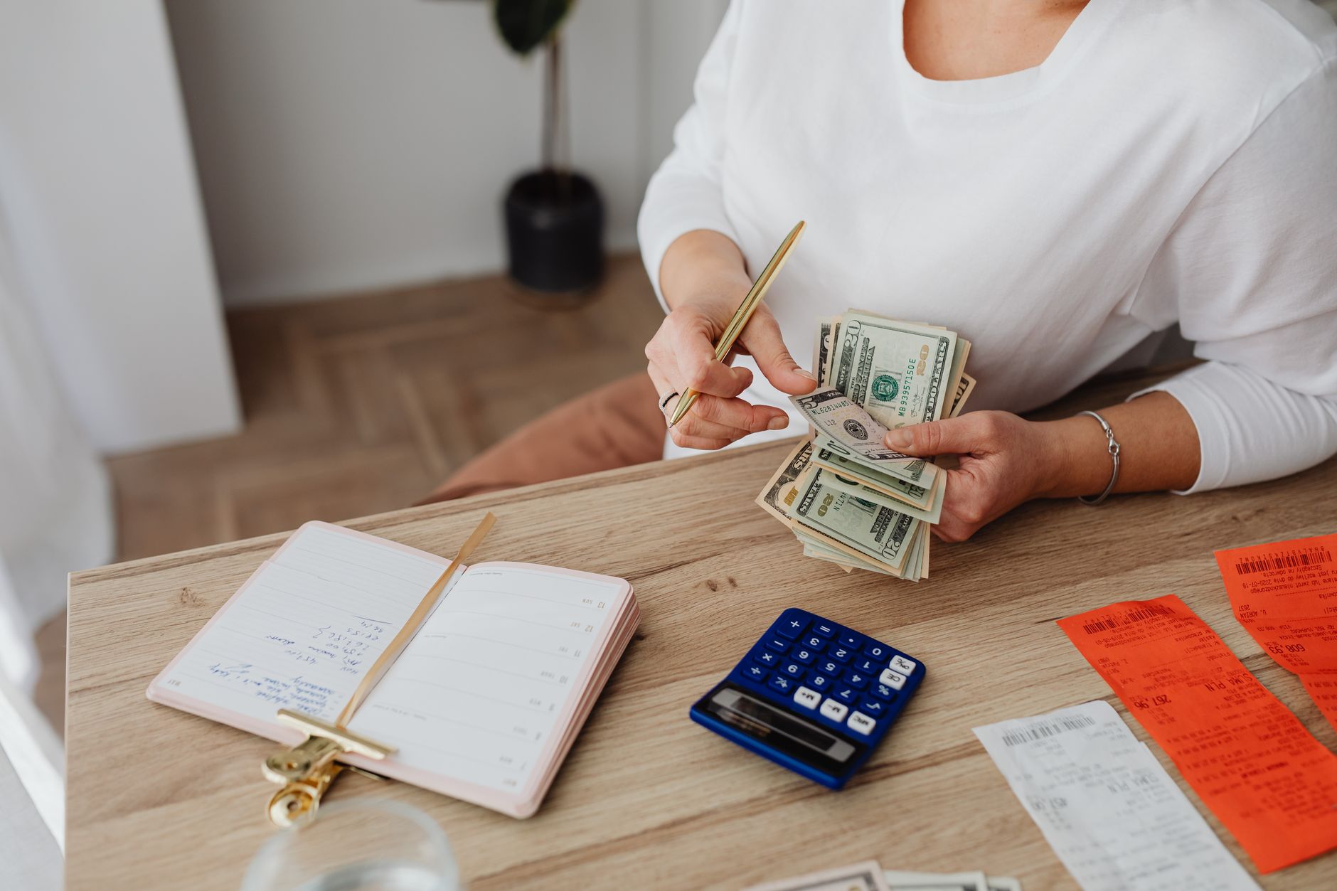 Woman sorting finances with a calculator, cash, and receipts at a desk — UPI Study