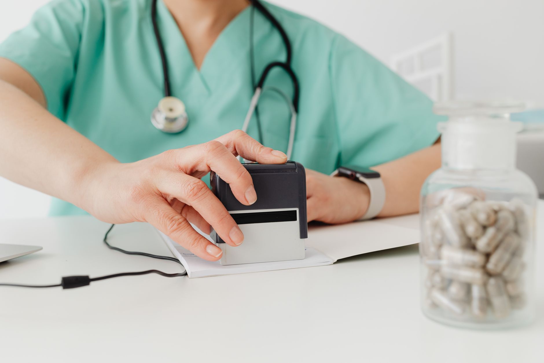 Close-up of a doctor stamping a prescription with a bottle of pills on a desk — UPI Study