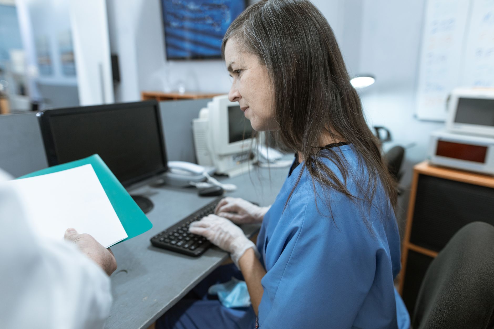 Nurse in scrubs typing on a keyboard at a medical workstation — UPI Study