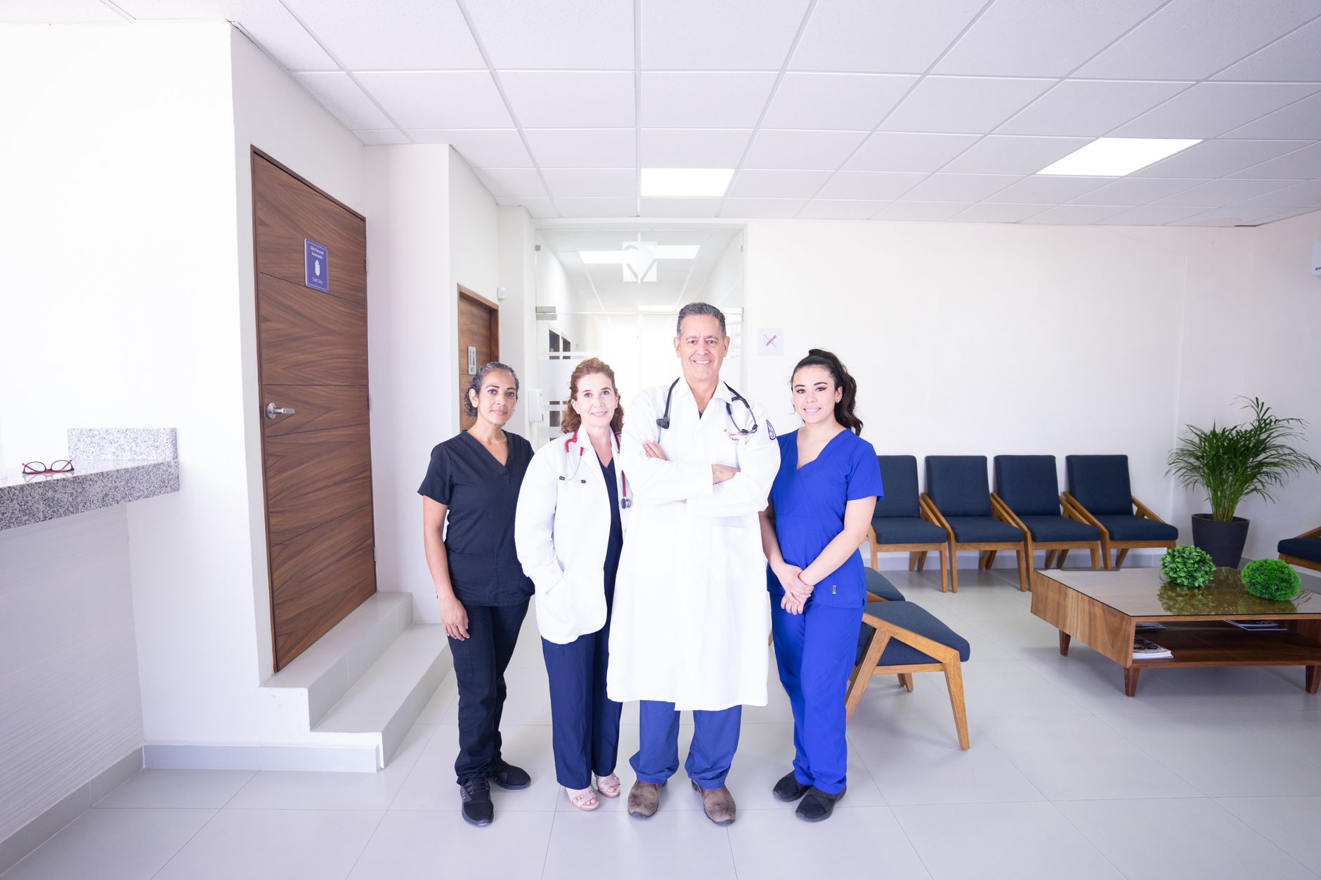 Diverse medical practitioners in uniforms, smiling in a modern hospital waiting area — UPI Study