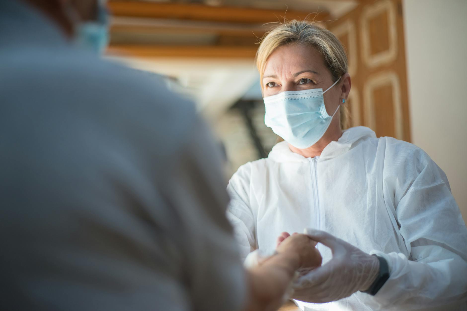 A healthcare worker in protective gear providing care indoors. Focused face with surgical mask — UPI Study