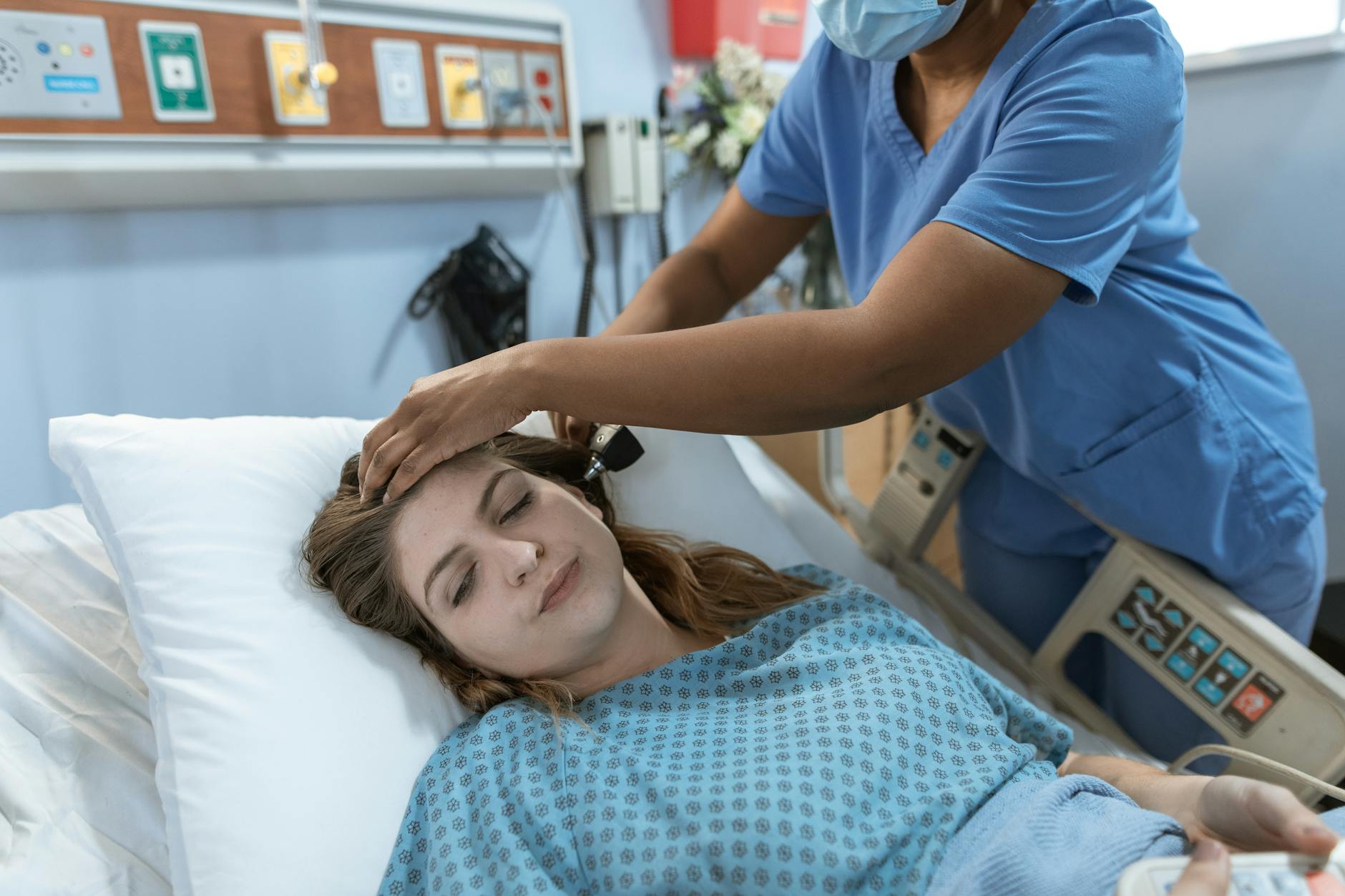 Crop African American female doctor with professional equipment doing examination of ear of woman lying on bed in hospital ward — UPI Study