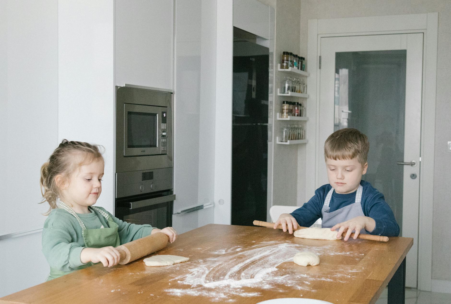 Two children baking at home in a modern Istanbul kitchen, rolling dough with focused expressions — UPI Study