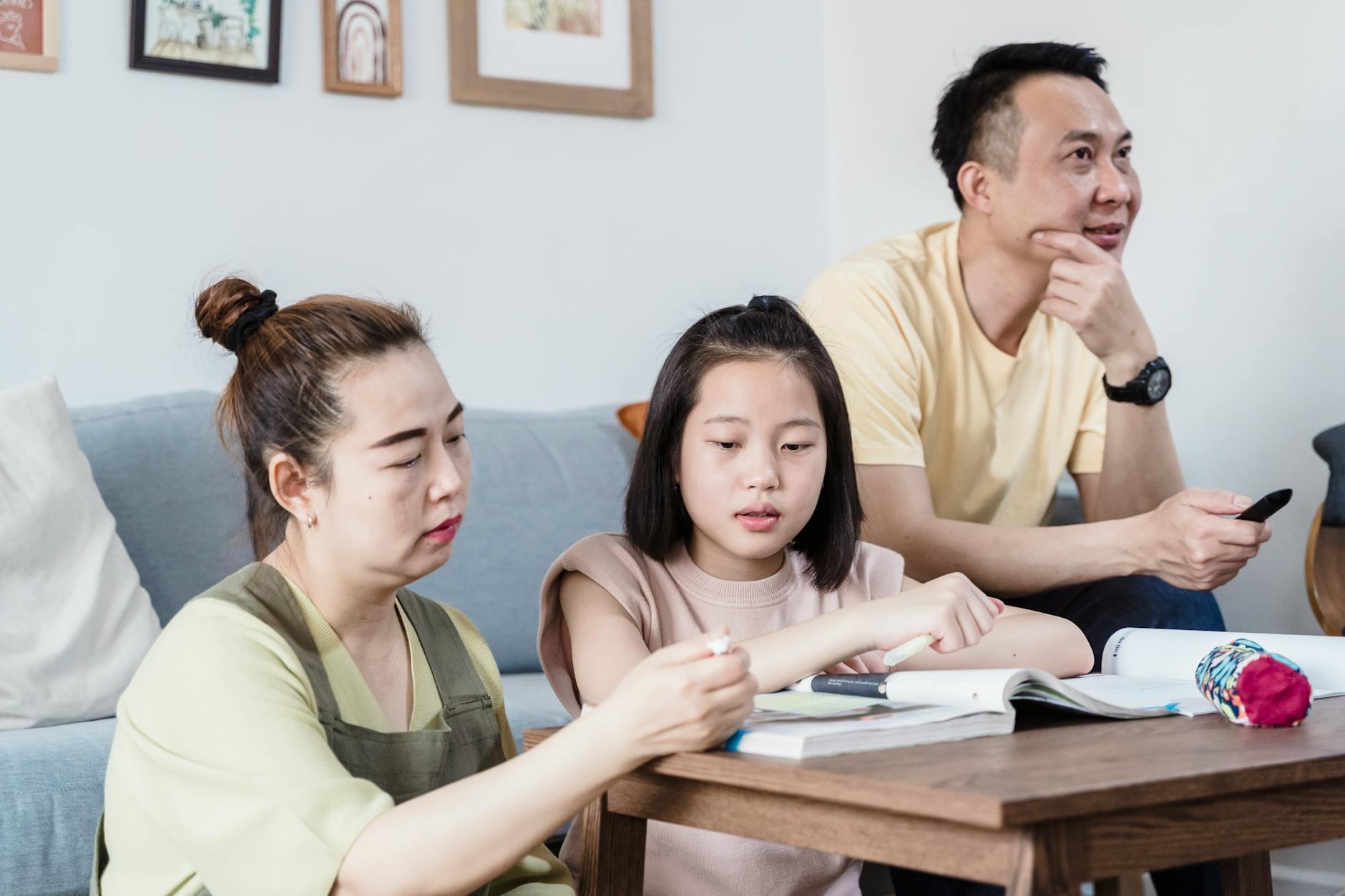A family helping their daughter with homework in the living room, promoting togetherness — UPI Study