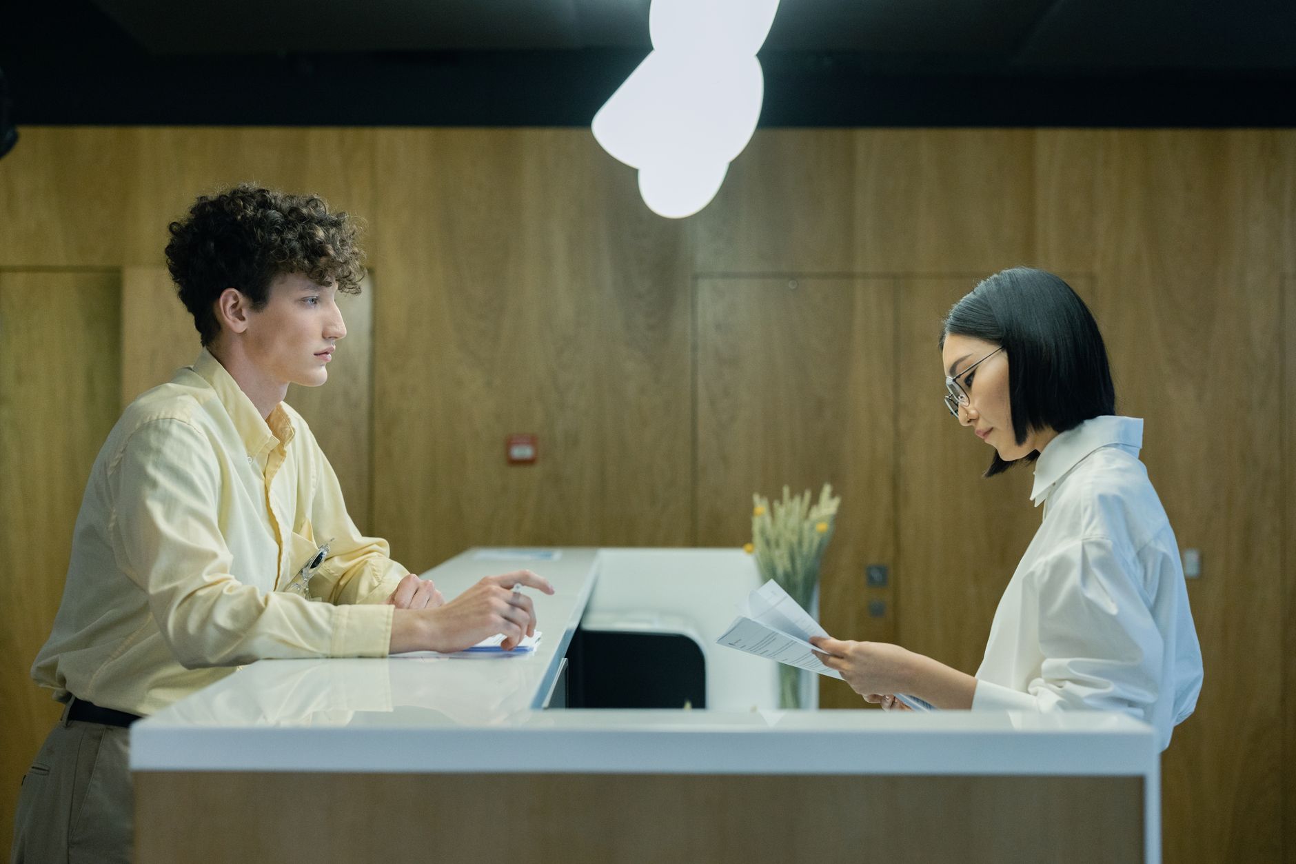 A young man and woman interacting at a modern office reception desk indoors — UPI Study