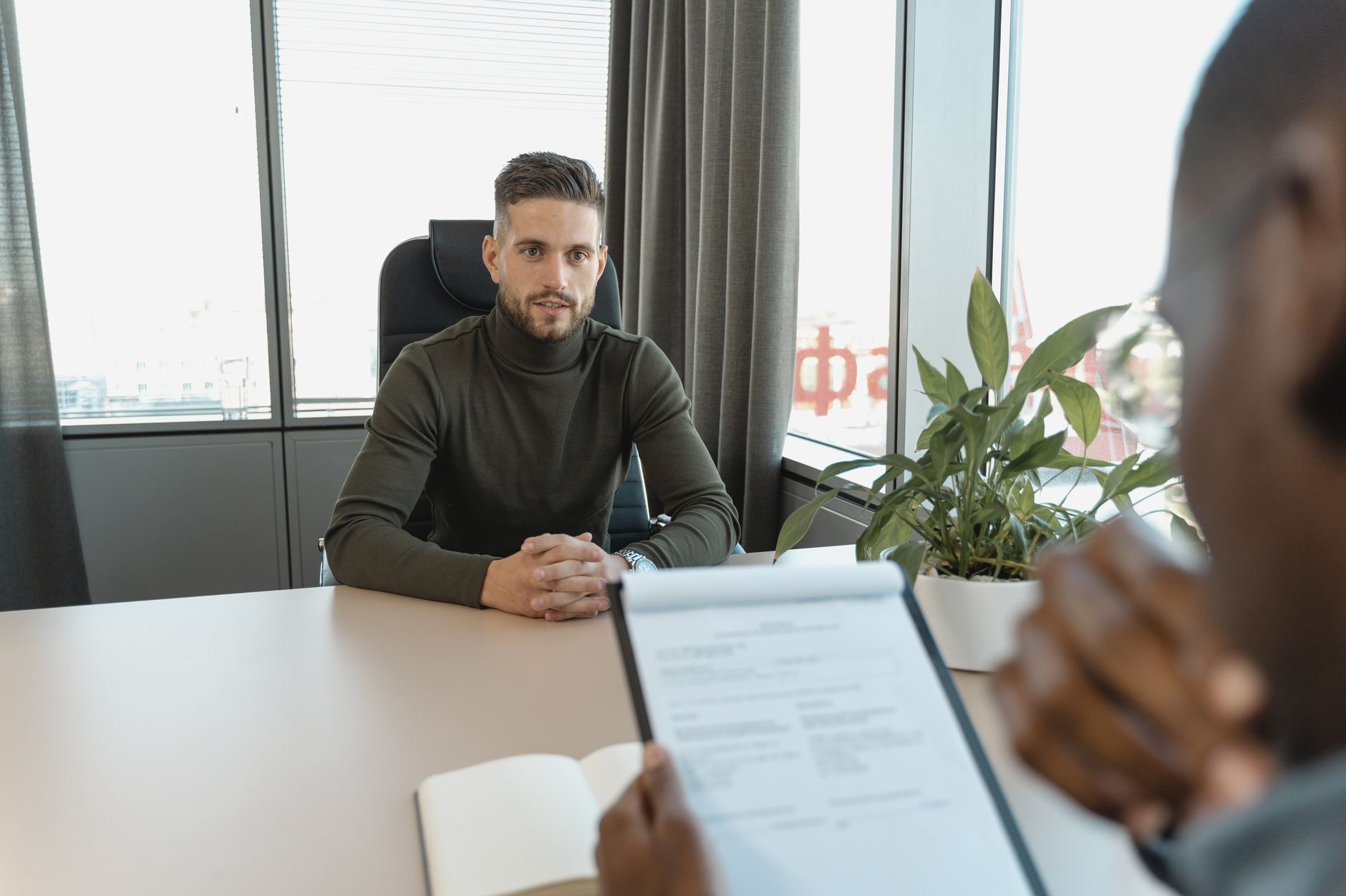 Professional man in turtleneck at office desk during an interview — UPI Study