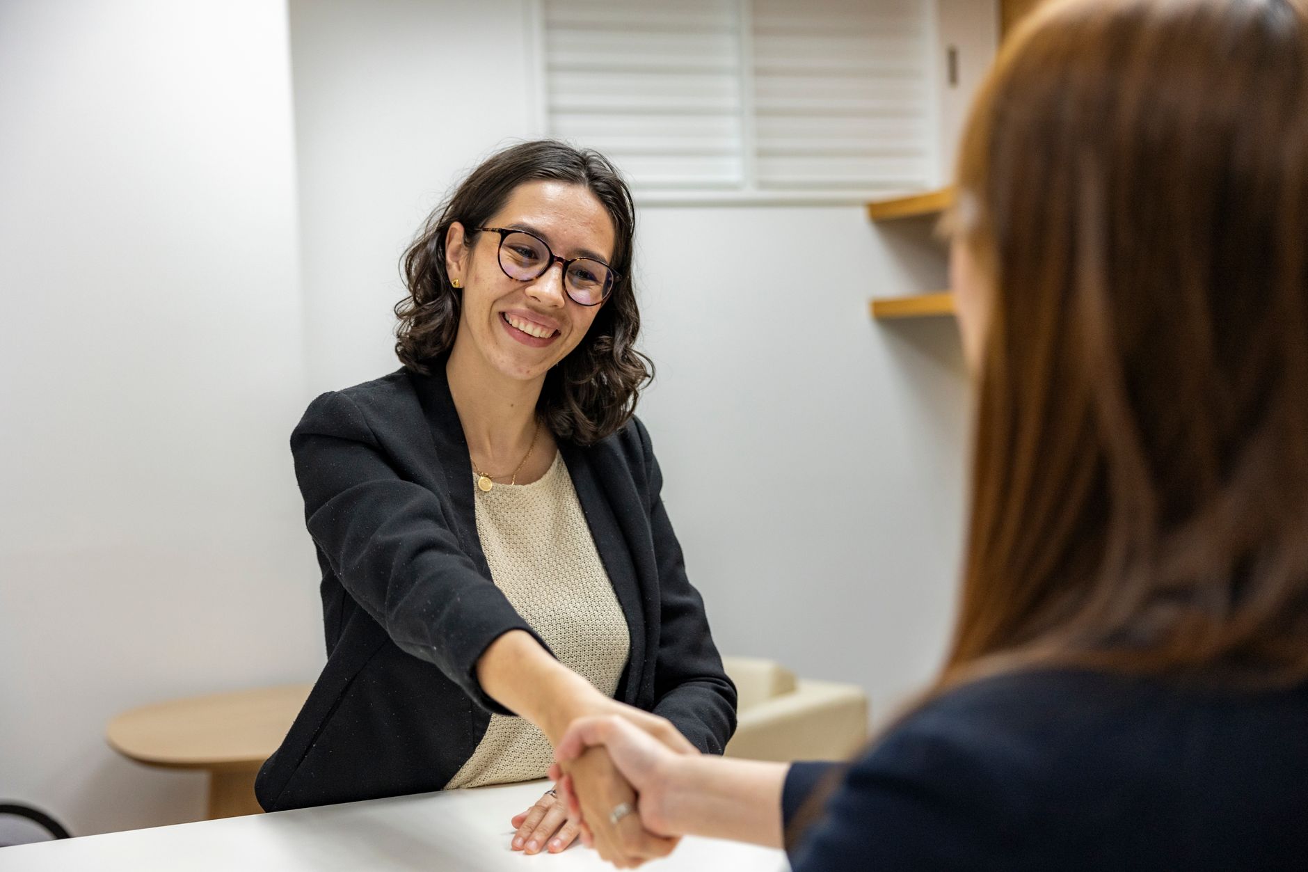 Businesswomen shaking hands in an office, representing a successful job interview or partnership — UPI Study