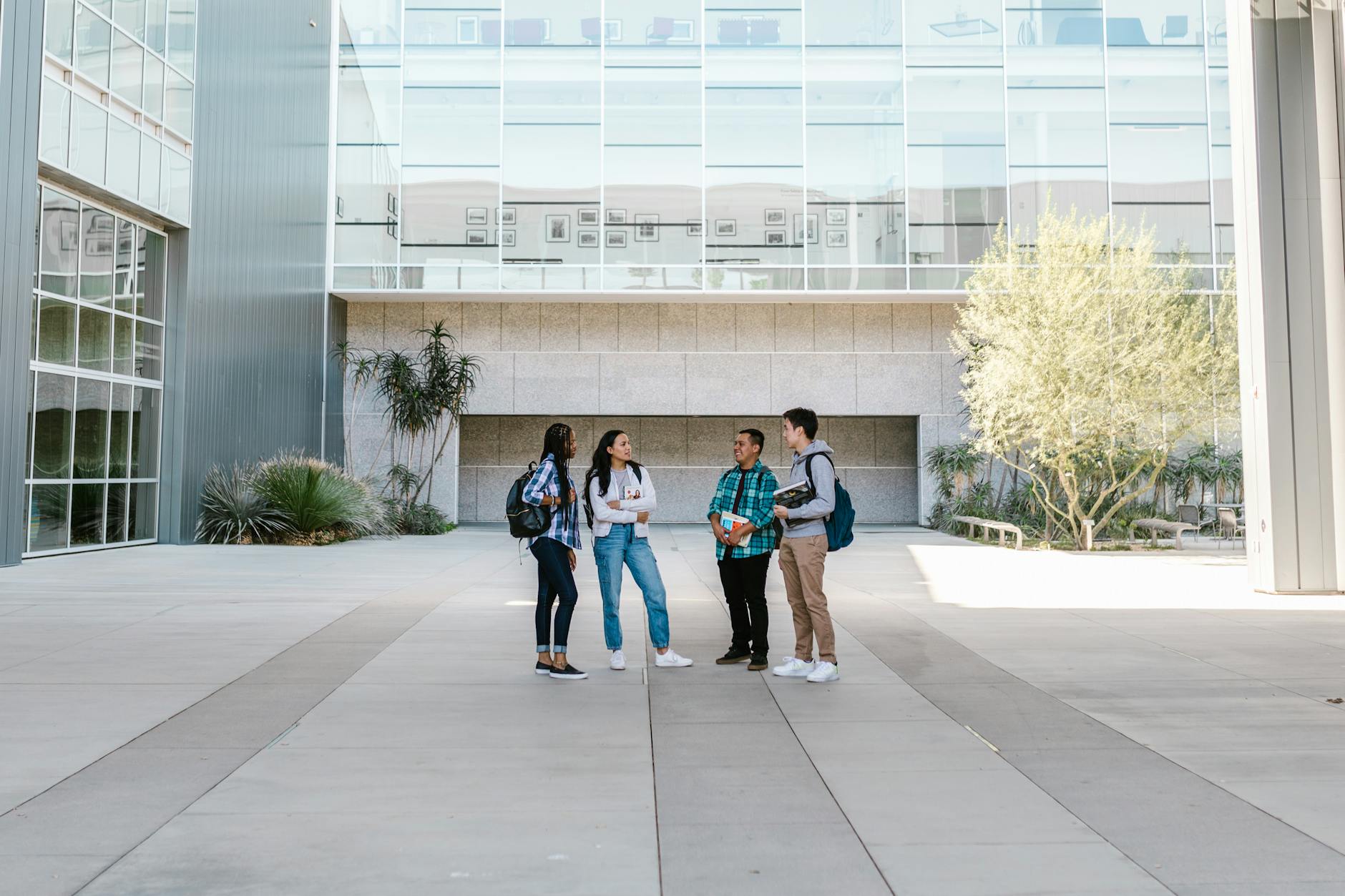 A group of diverse college students standing and talking in a sunny outdoor campus setting — UPI Study