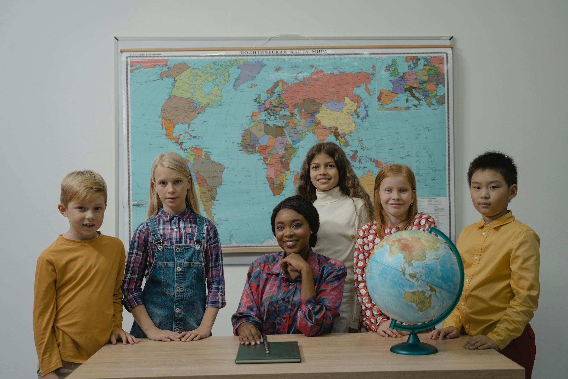 A diverse group of students with a teacher in a classroom setting featuring a globe and world map — UPI Study