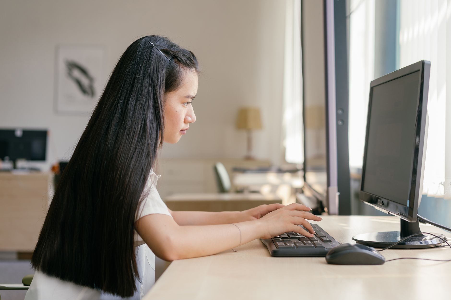 A young woman working intently on a computer in a bright, modern office setting, embodying productivity — UPI Study