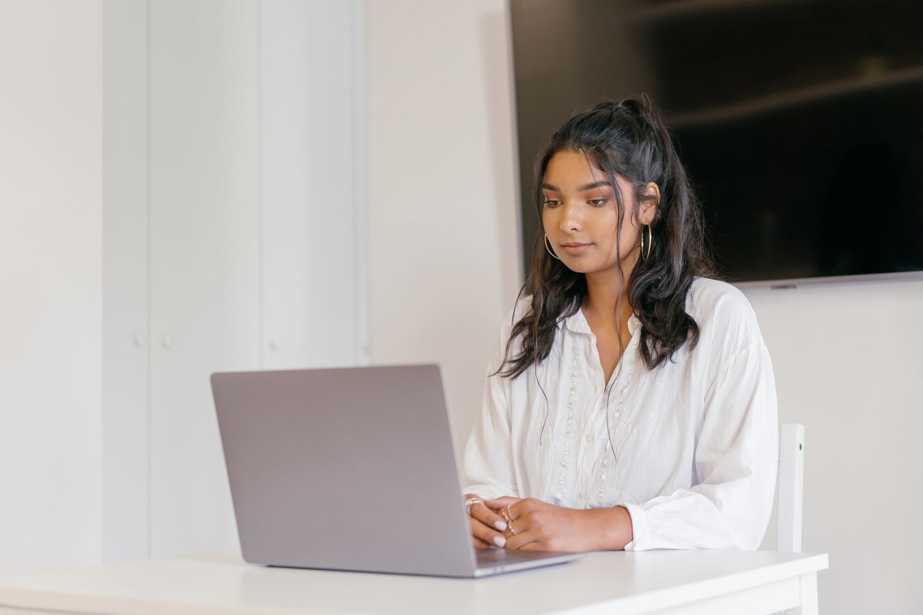 A young woman focused on studying with her laptop in a modern indoor setting — UPI Study