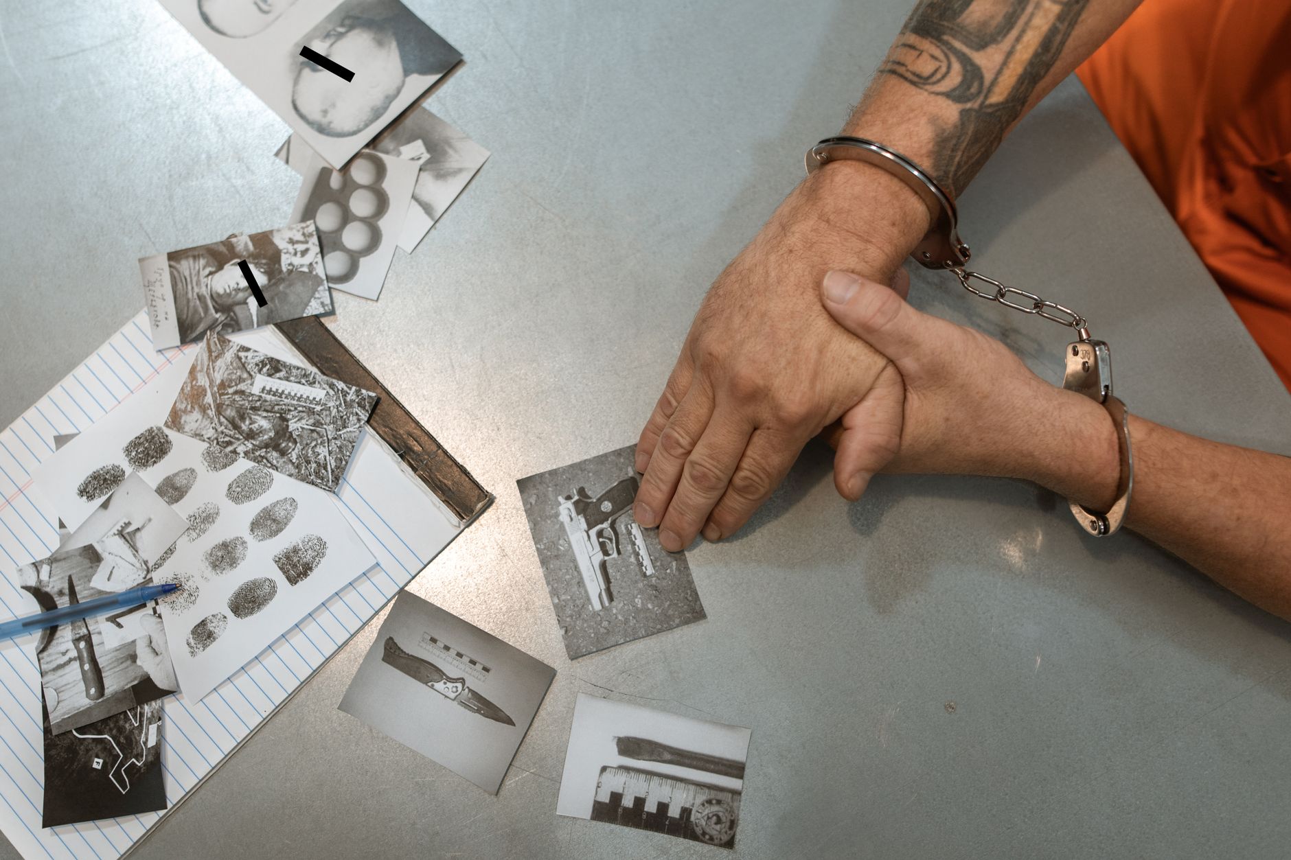 A handcuffed individual examines evidence photos and documents during an investigation — UPI Study