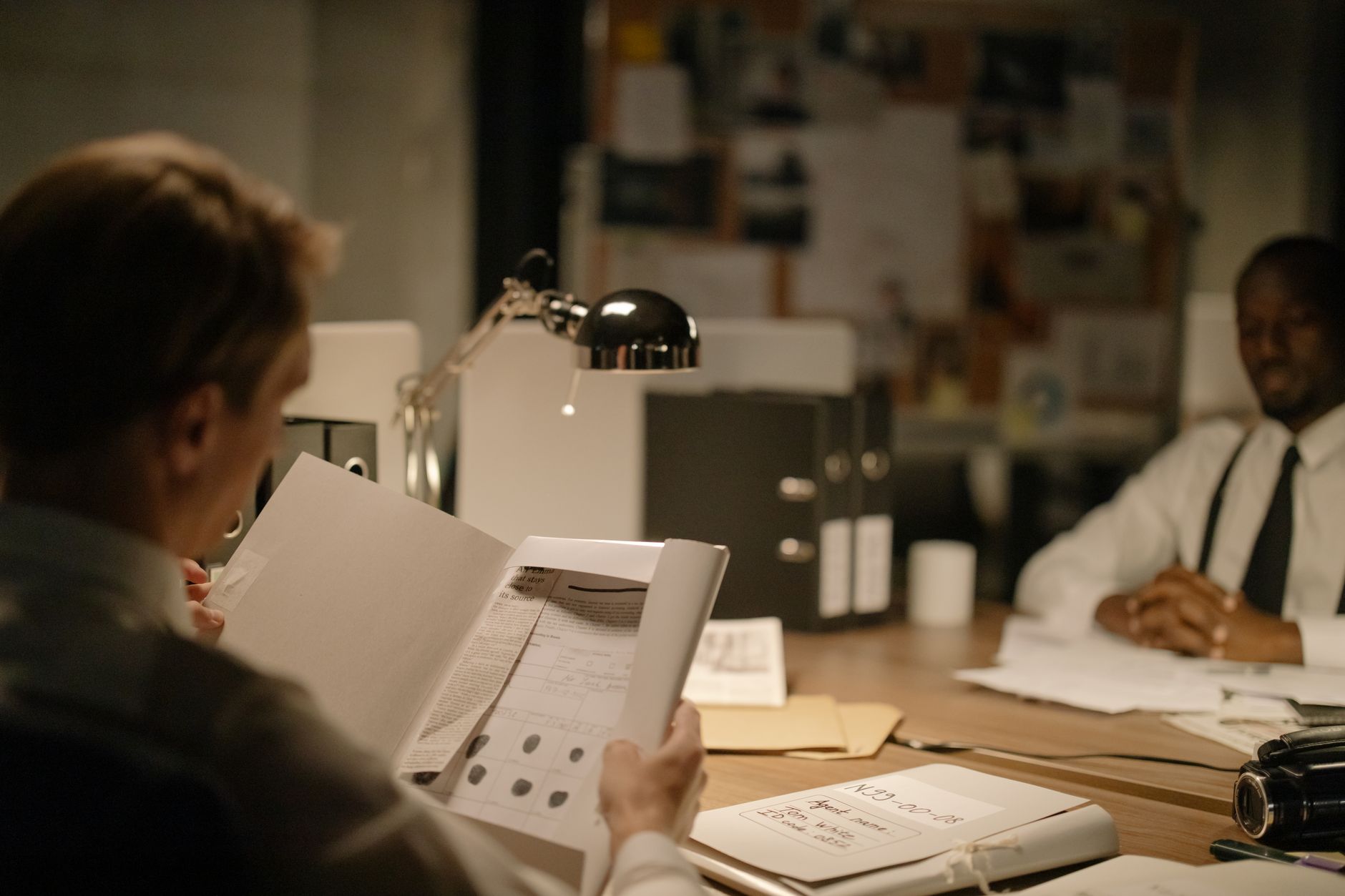 Detectives reviewing documents in a dimly lit office. Focus on investigation process — UPI Study