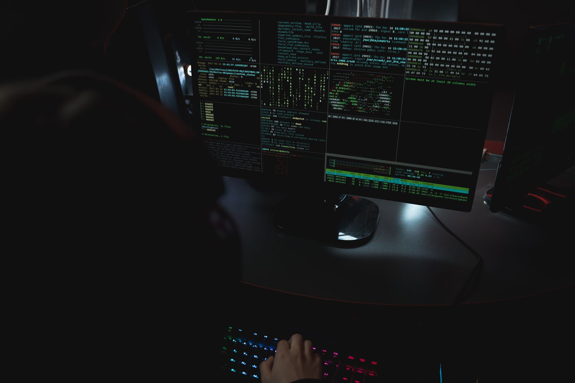 Dark room setup with code displayed on PC monitors highlighting cybersecurity themes — UPI Study