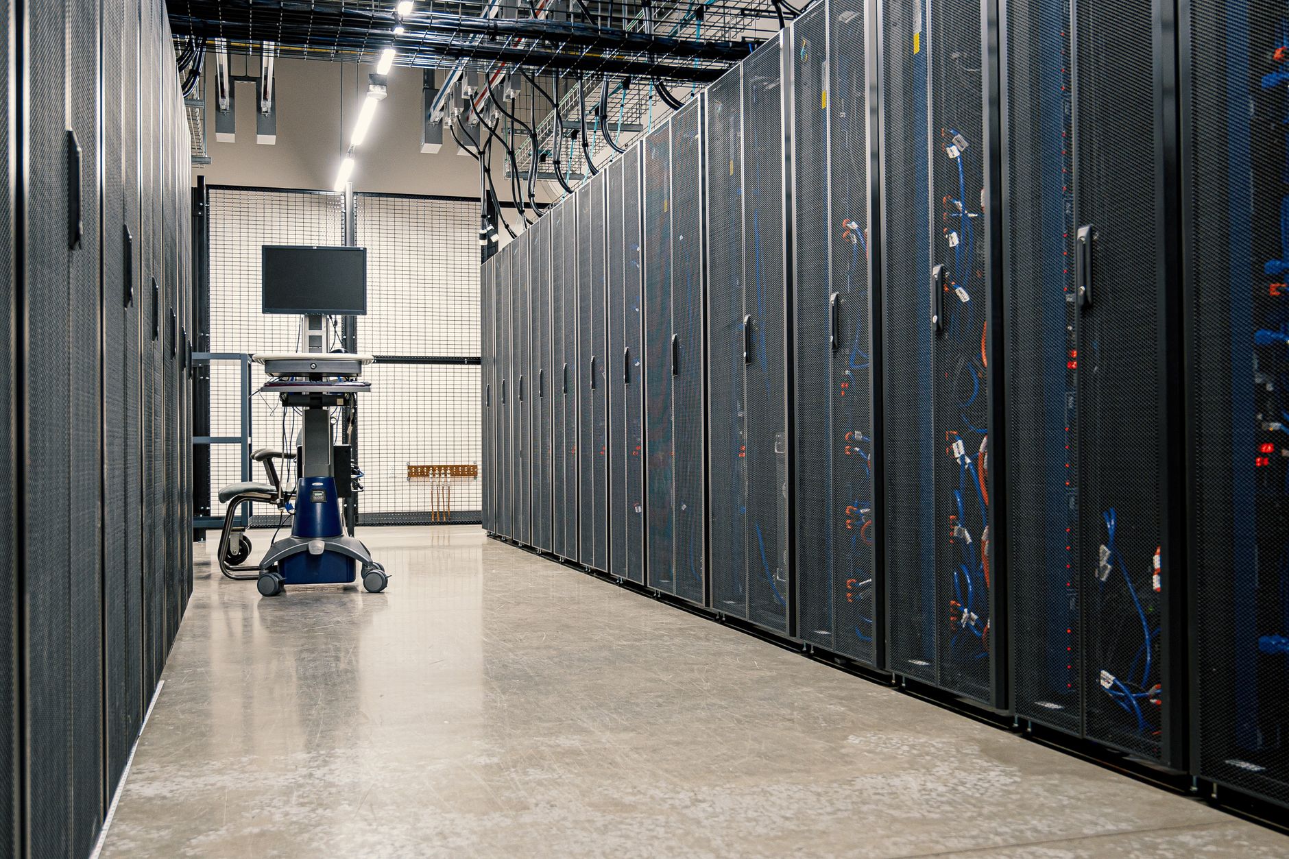 Steel framework cabinets housing servers networking devices and cables in contemporary equipped data center — UPI Study