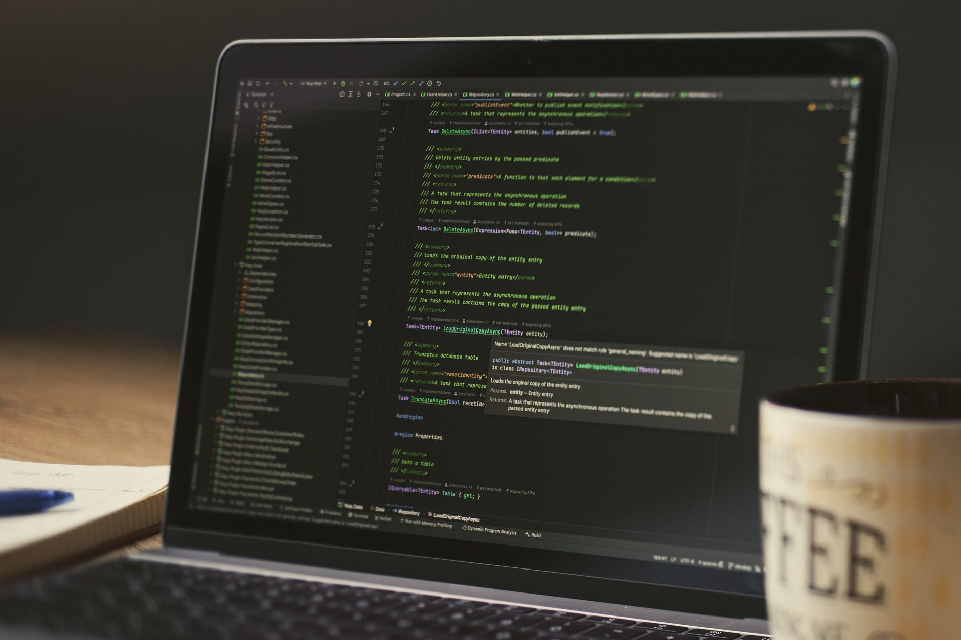 A close-up of a laptop displaying code in a dimly lit room with a coffee mug nearby — UPI Study