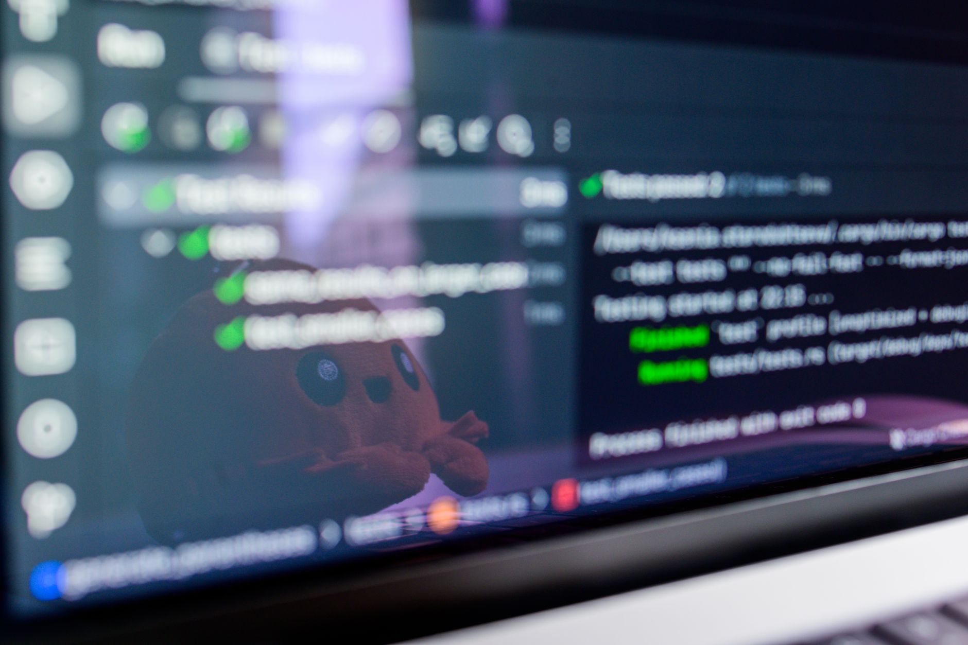 Close-up of a laptop screen displaying programming code with a cute plush toy reflecting — UPI Study