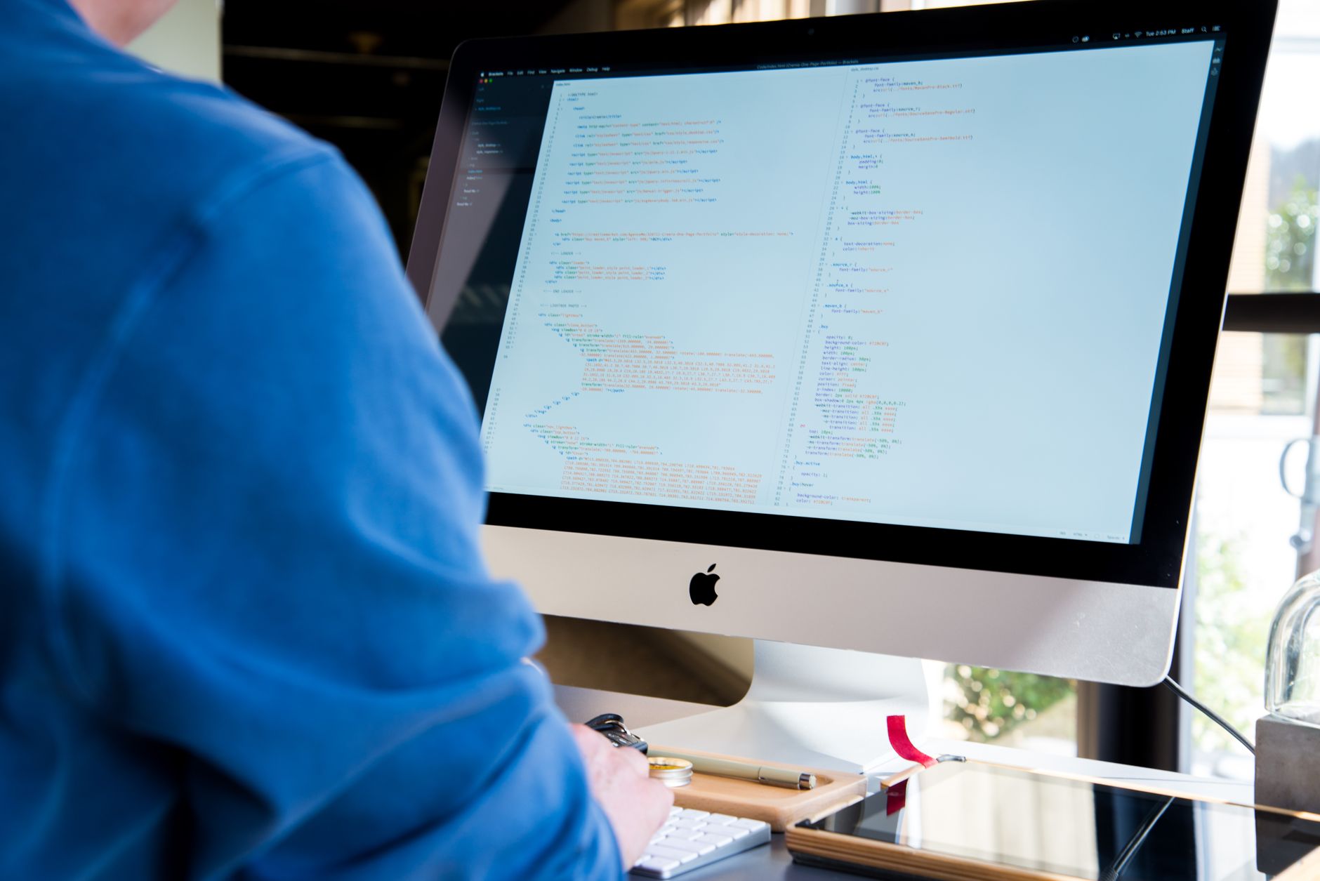 A programmer in a blue shirt coding on an iMac. Perfect for technology or work-related themes — UPI Study