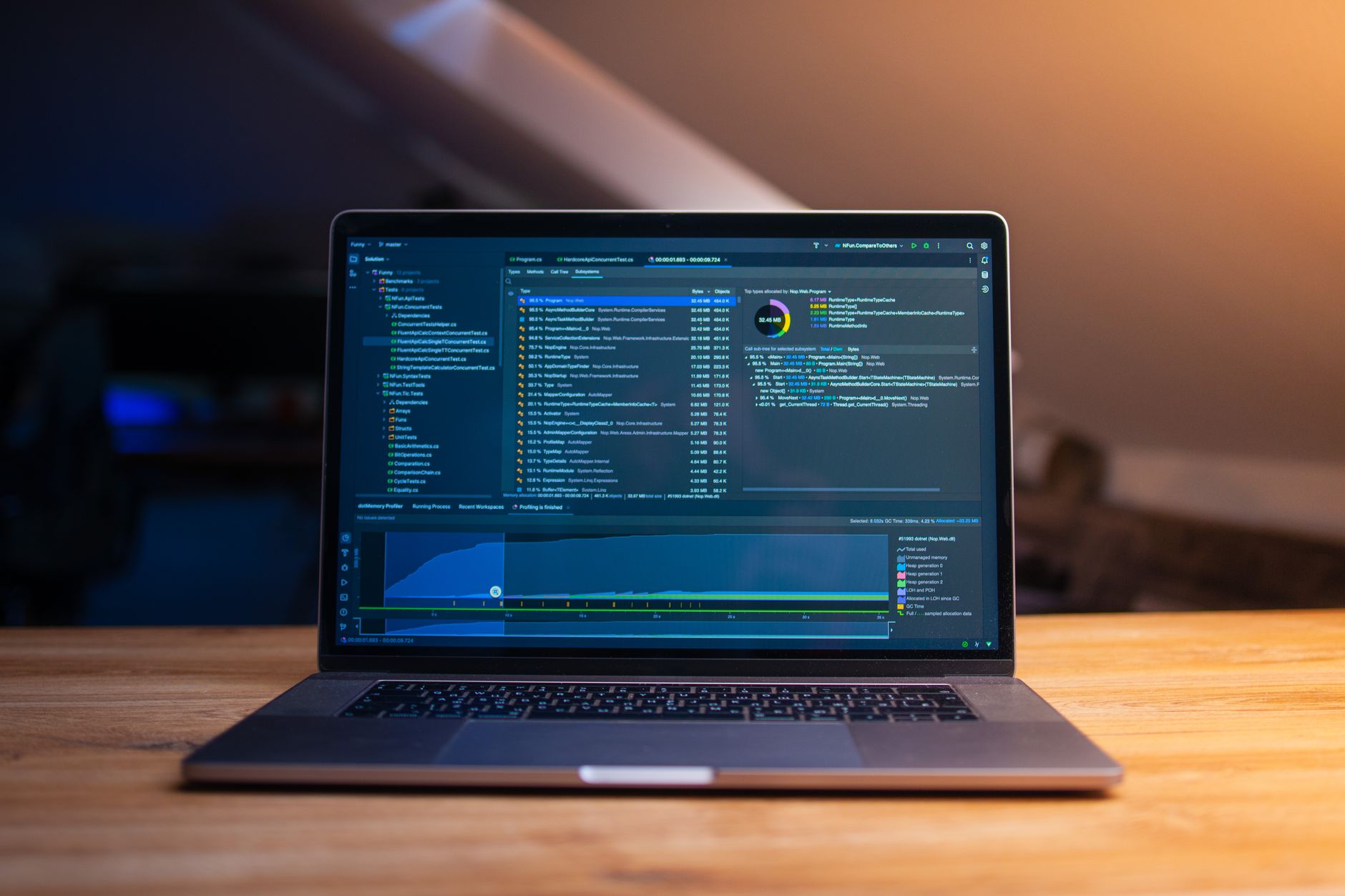A laptop displaying code on a wooden desk, in a dimly lit workspace — UPI Study