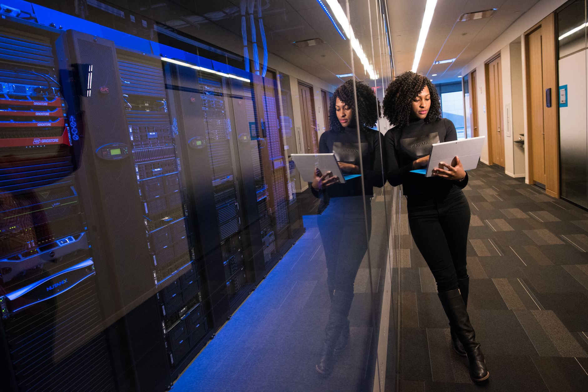 A woman using a laptop navigating a contemporary data center with mirrored servers — UPI Study
