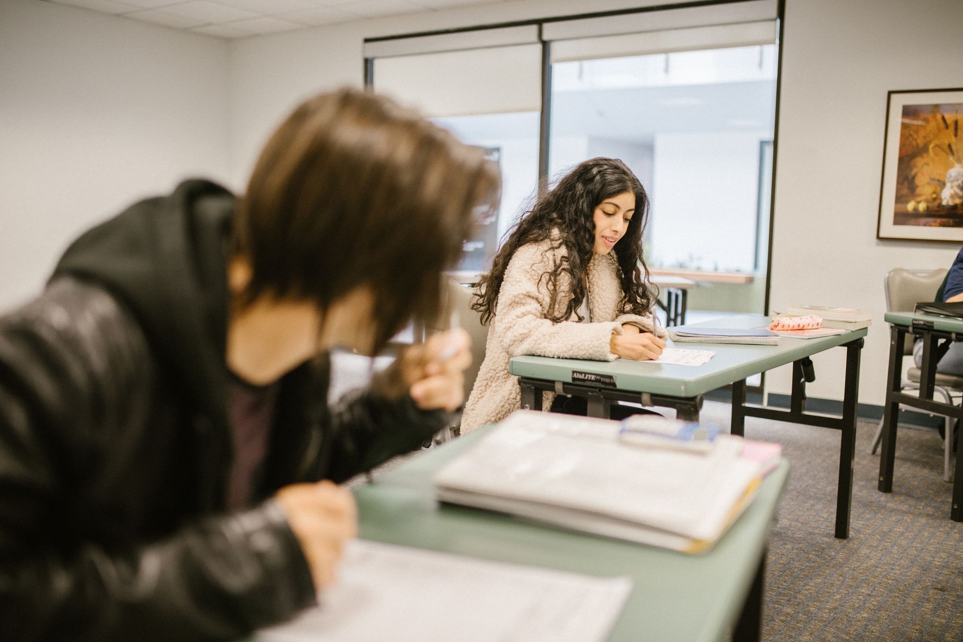 Two students focused on an exam in a classroom setting during daylight — UPI Study