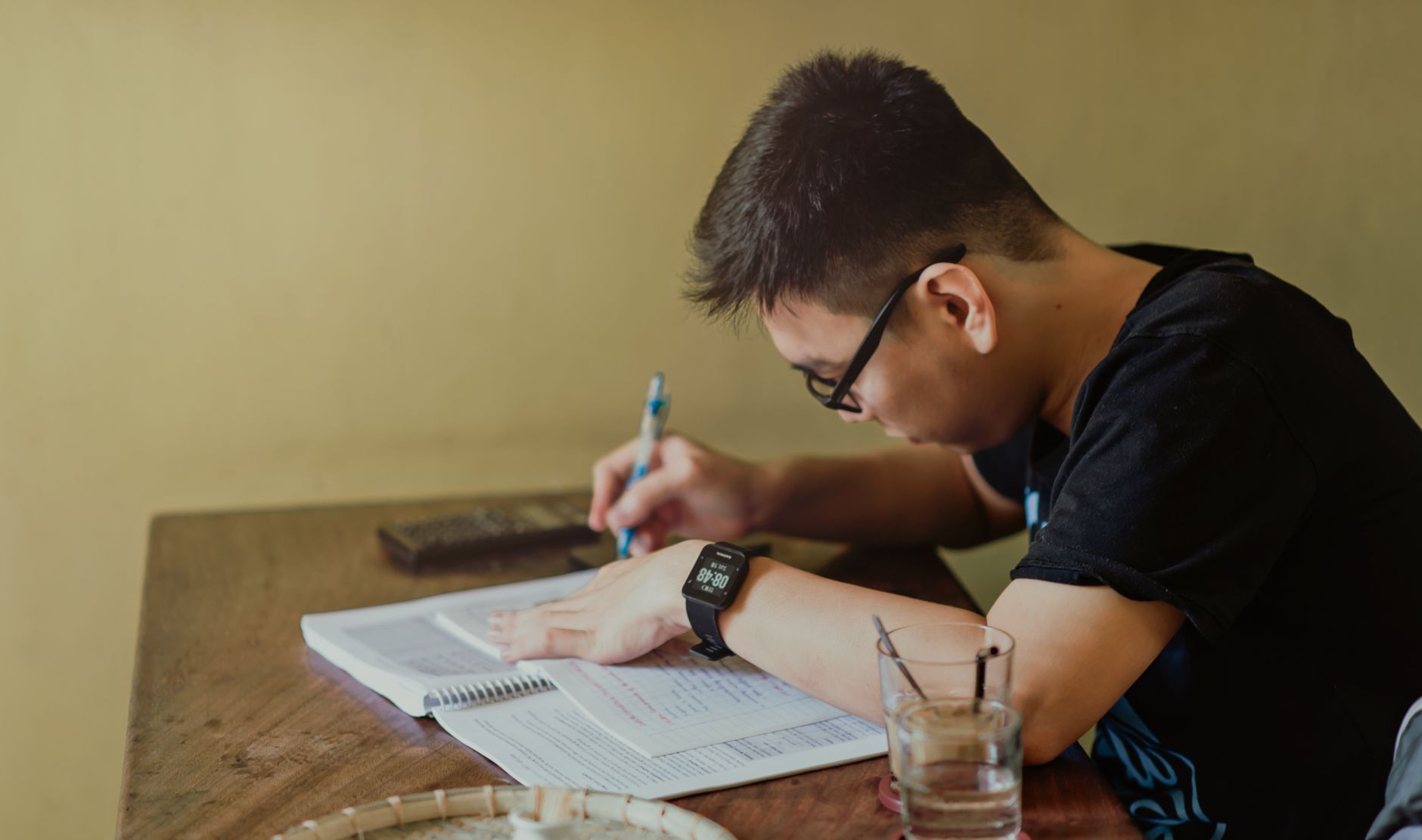 A young man concentrates on studying at his desk, taking notes indoors — UPI Study