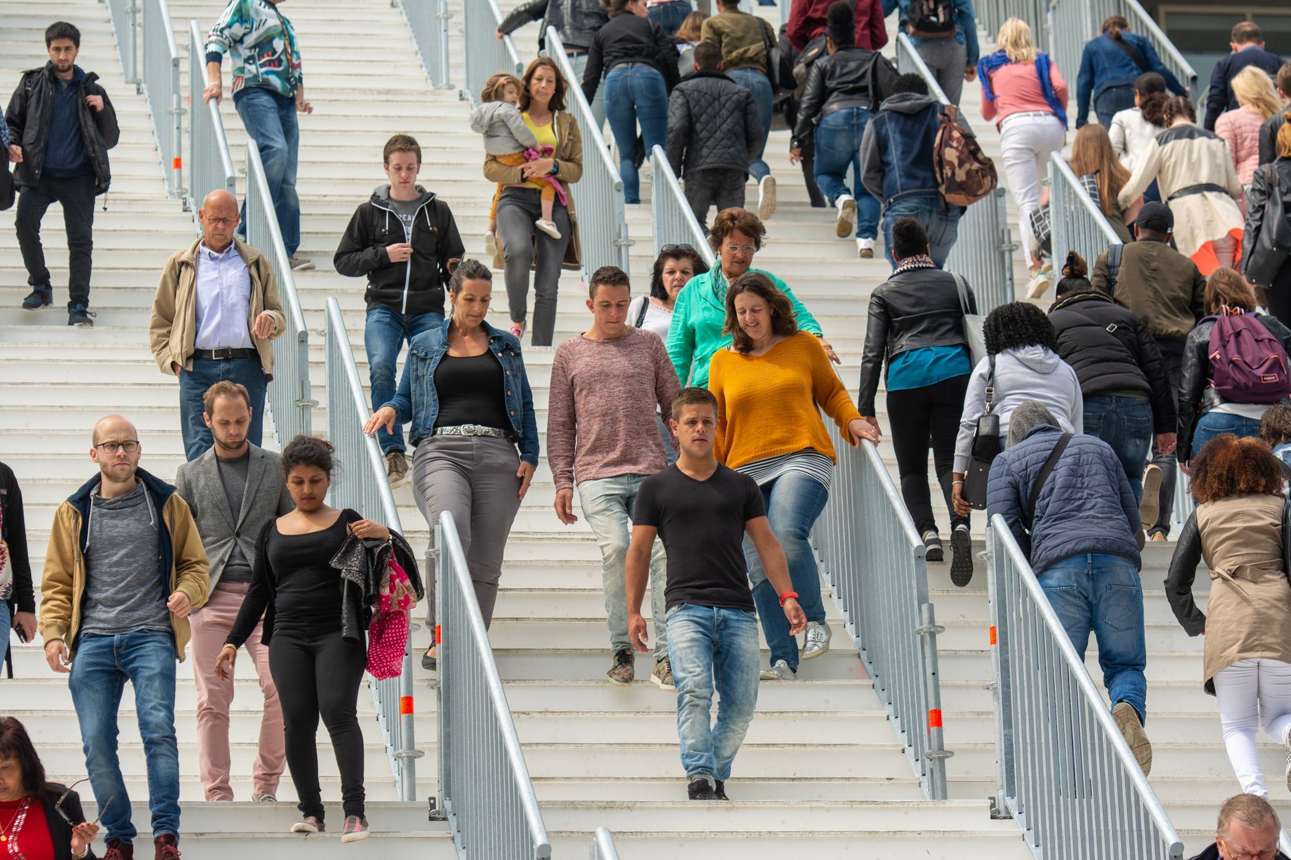 A diverse crowd of people walking downstairs in a bustling urban environment, showcasing everyday life — UPI Study