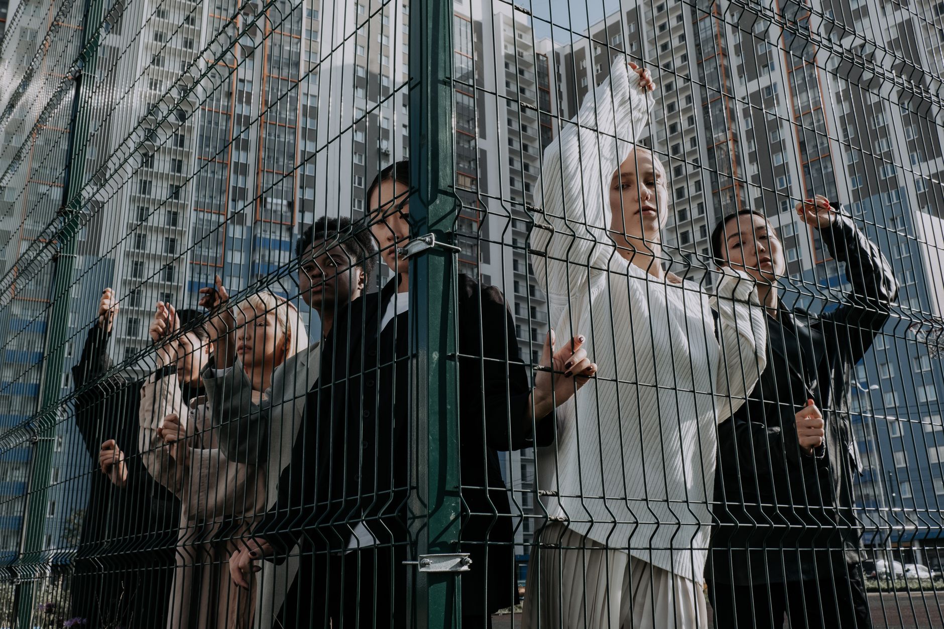 Stylish diverse group posing behind urban fence with high-rise backdrop — UPI Study