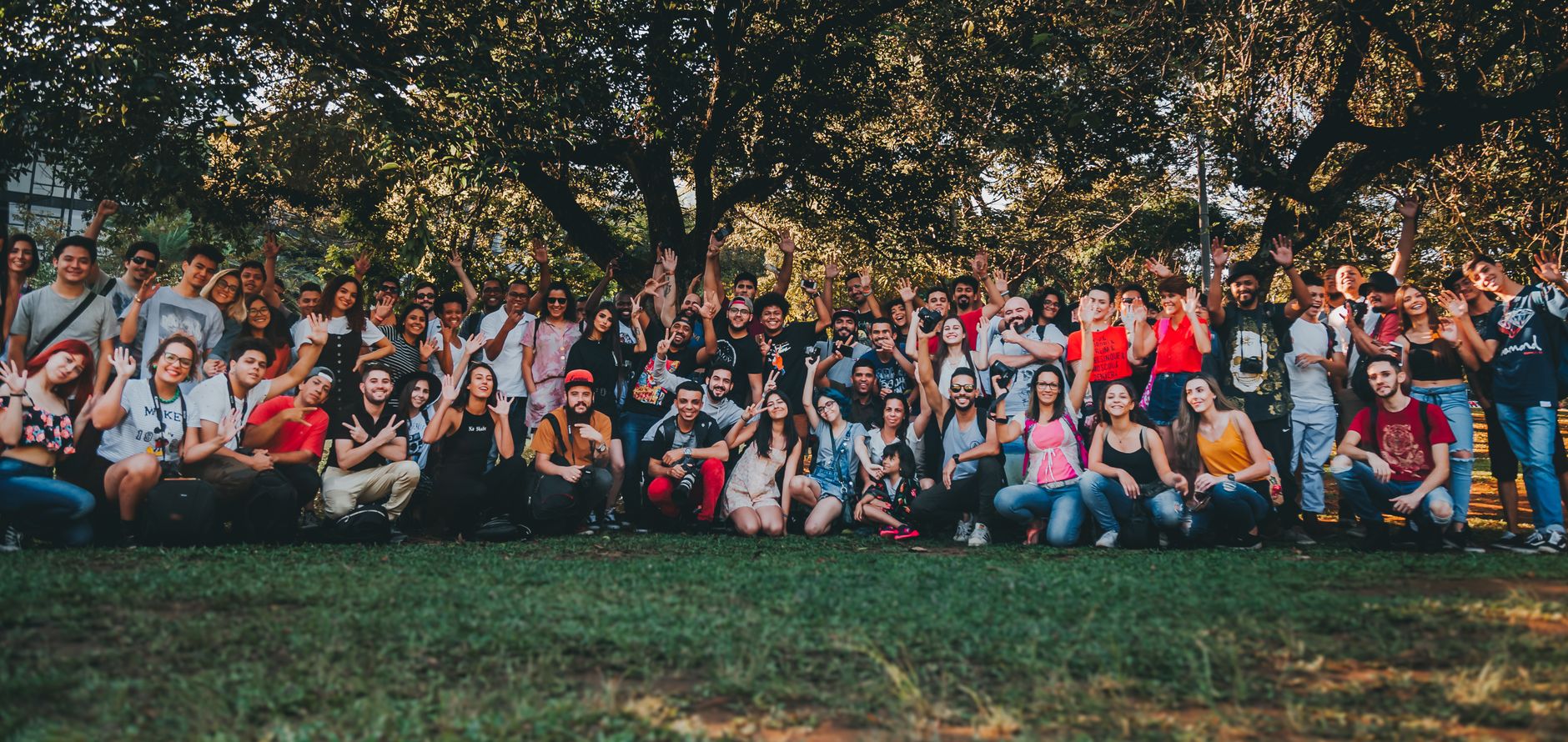 A diverse group of people gathering outdoors in a park, celebrating together with raised hands — UPI Study