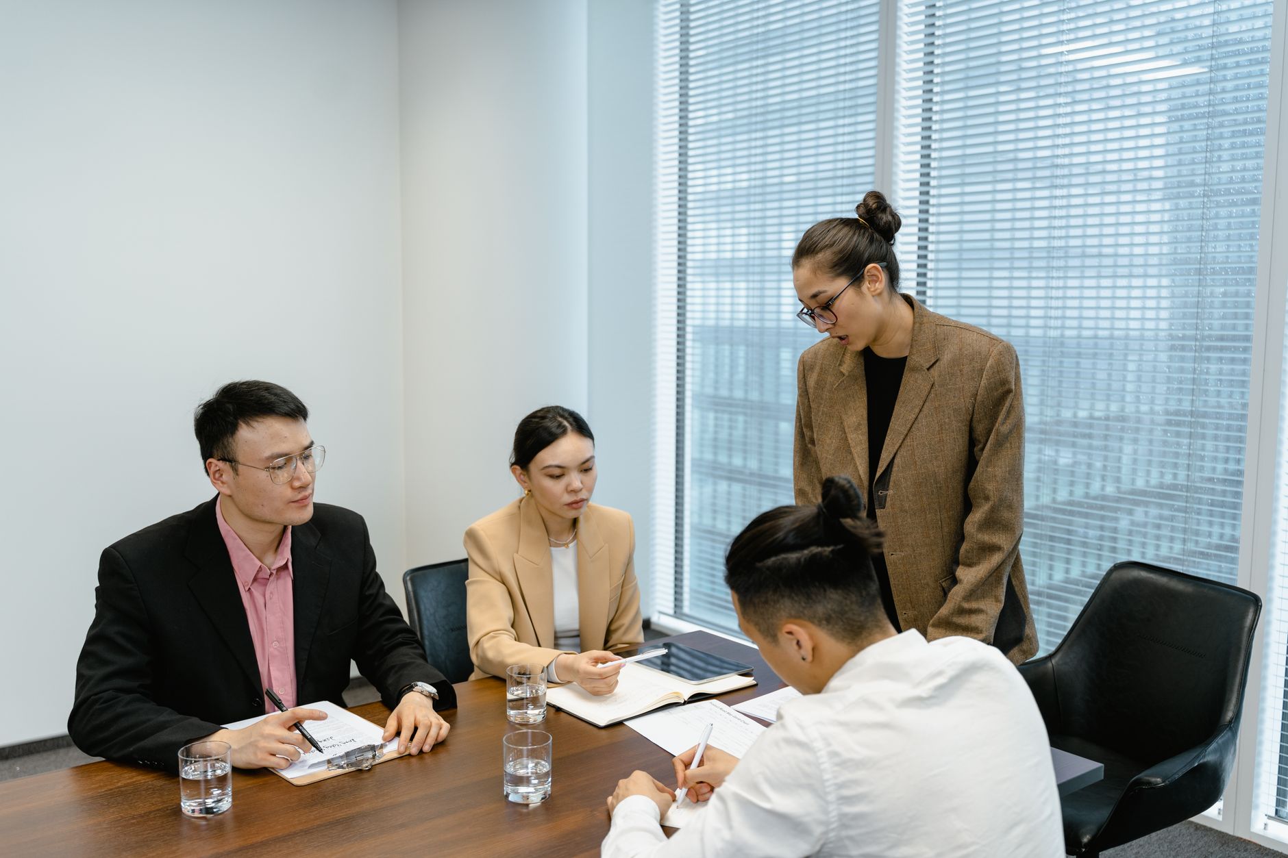 A group of business professionals engaged in a team meeting in a modern office setting — UPI Study