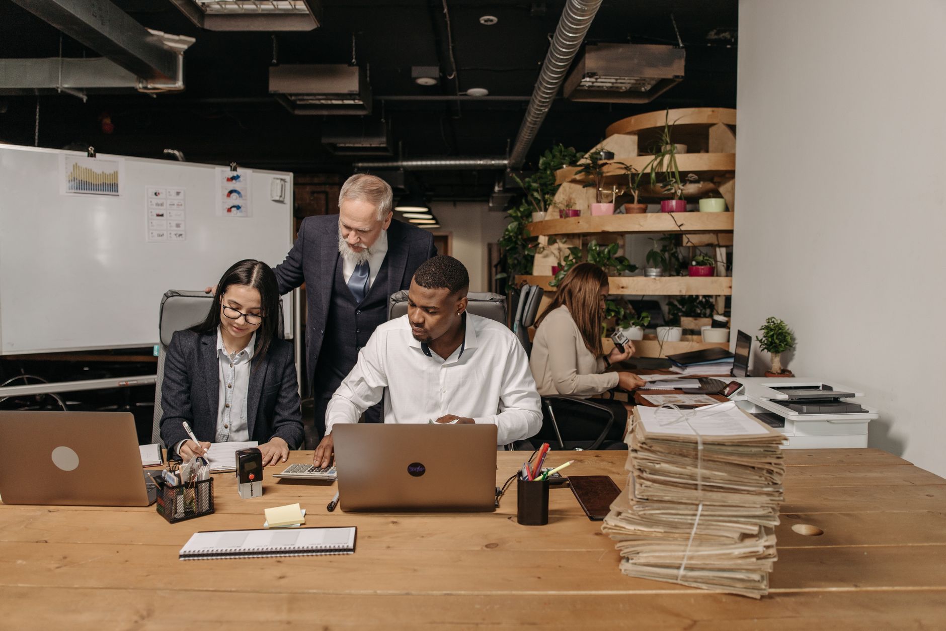 Team of professionals working collaboratively in a modern office environment with documents and laptops — UPI Study