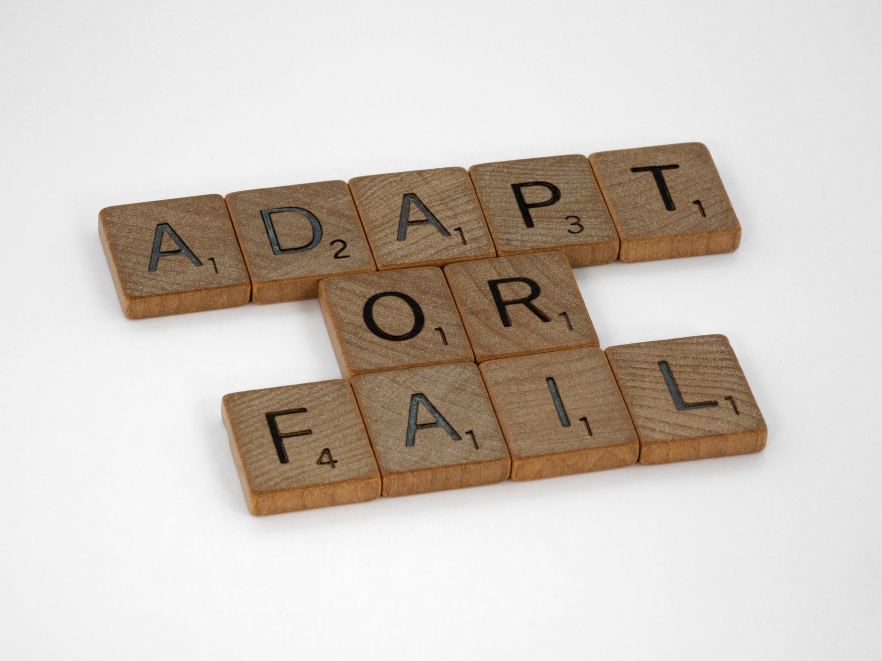 Scrabble tiles spell 'Adapt or Fail' on a white background, conveying a motivational message — UPI Study