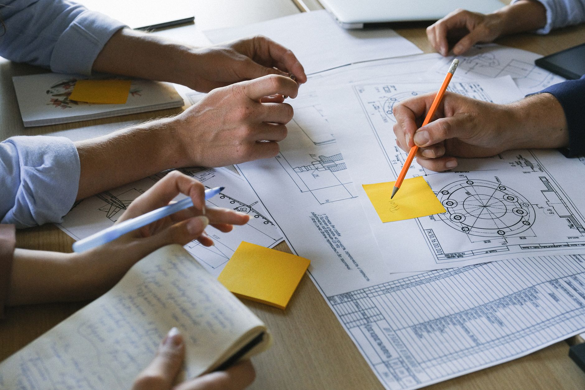 Crop anonymous coworkers sitting at table with documents and discussing project during brainstorm in light office in daytime — UPI Study