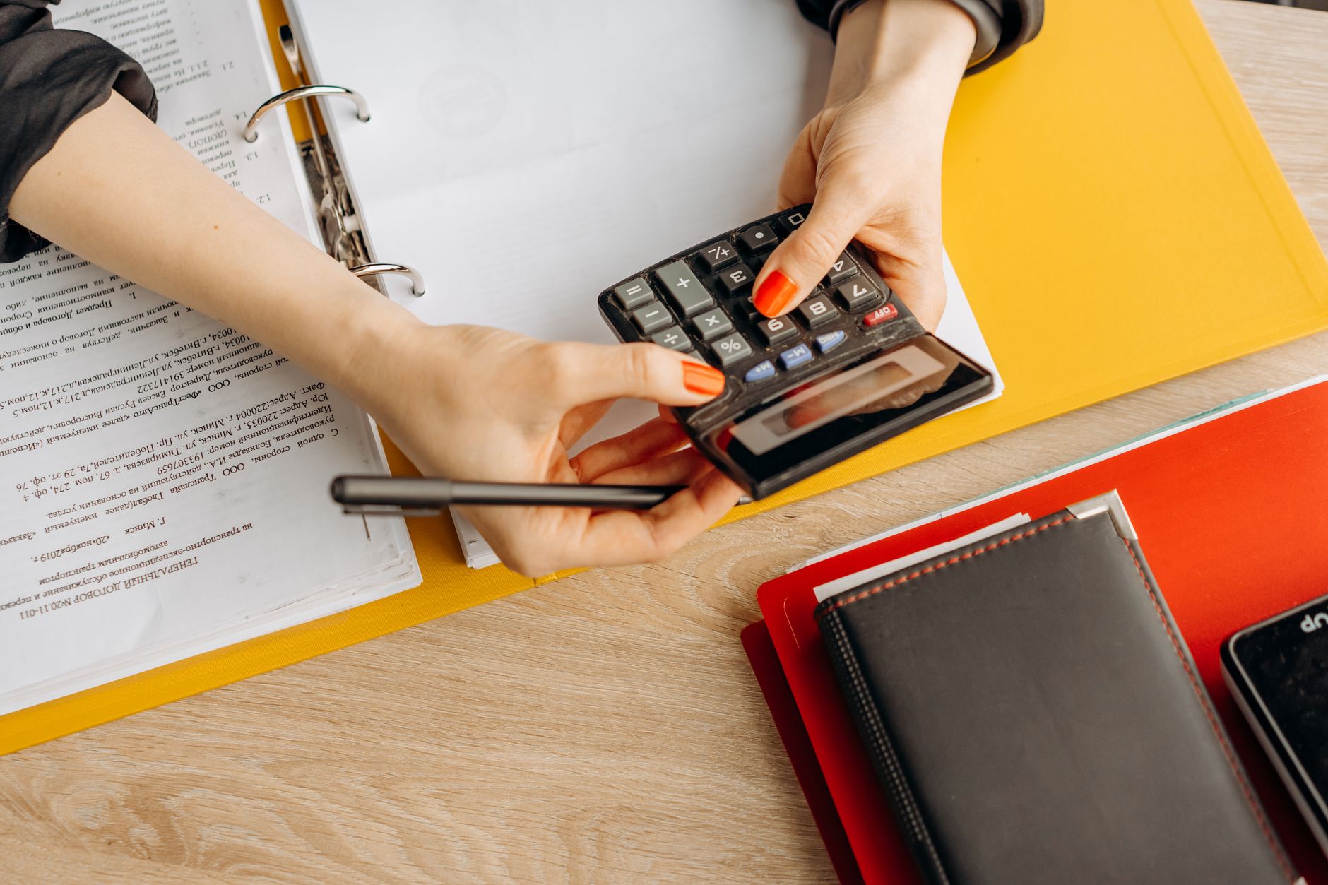 Hands using a calculator at a desk with documents and folders, ideal for finance or accounting themes — UPI Study