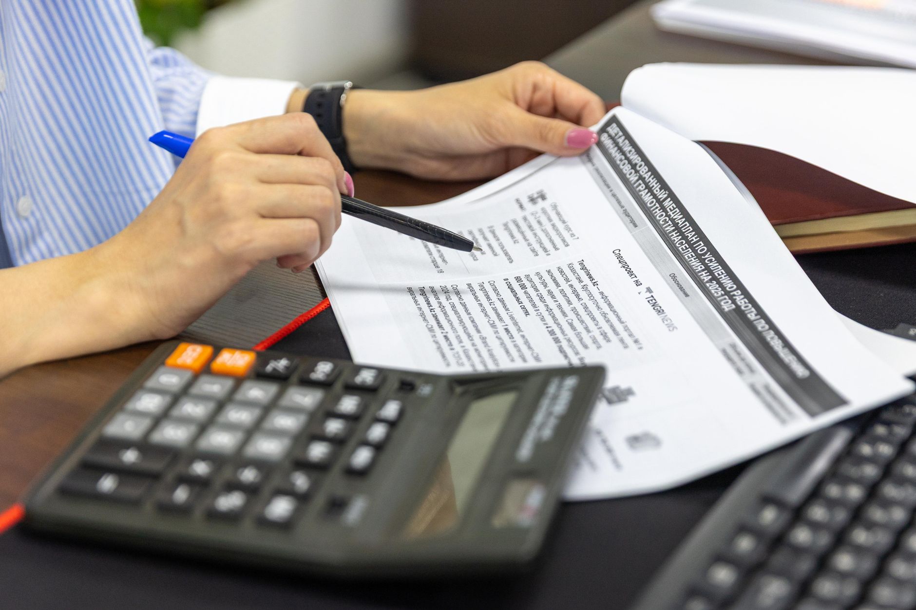 Close-up of a person analyzing financial documents using a calculator and pen — UPI Study