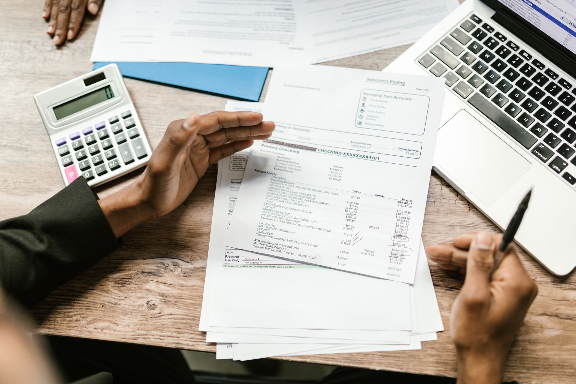 Hands holding financial documents with calculator and laptop on office desk, business analysis scene — UPI Study