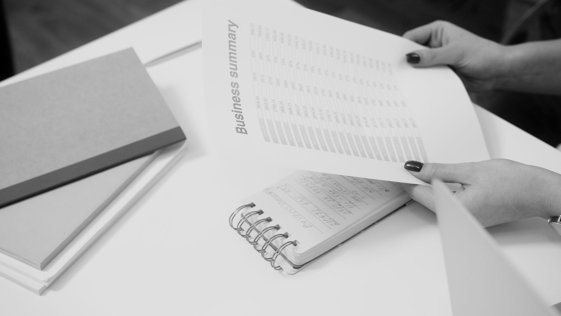 Black and white image of a businesswoman reviewing a business summary on paper — UPI Study