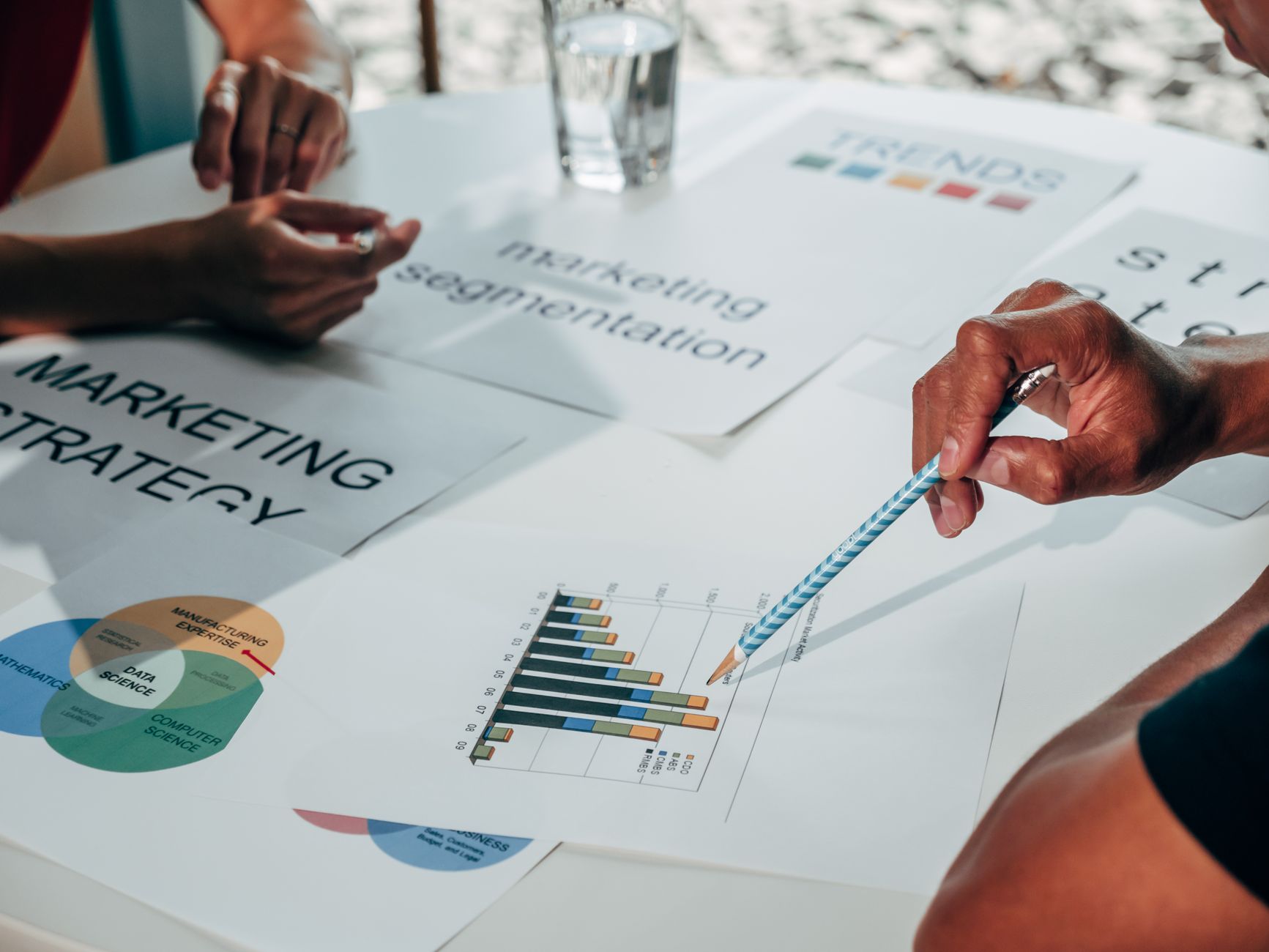 Team working on marketing strategy using data charts and papers in an office meeting — UPI Study