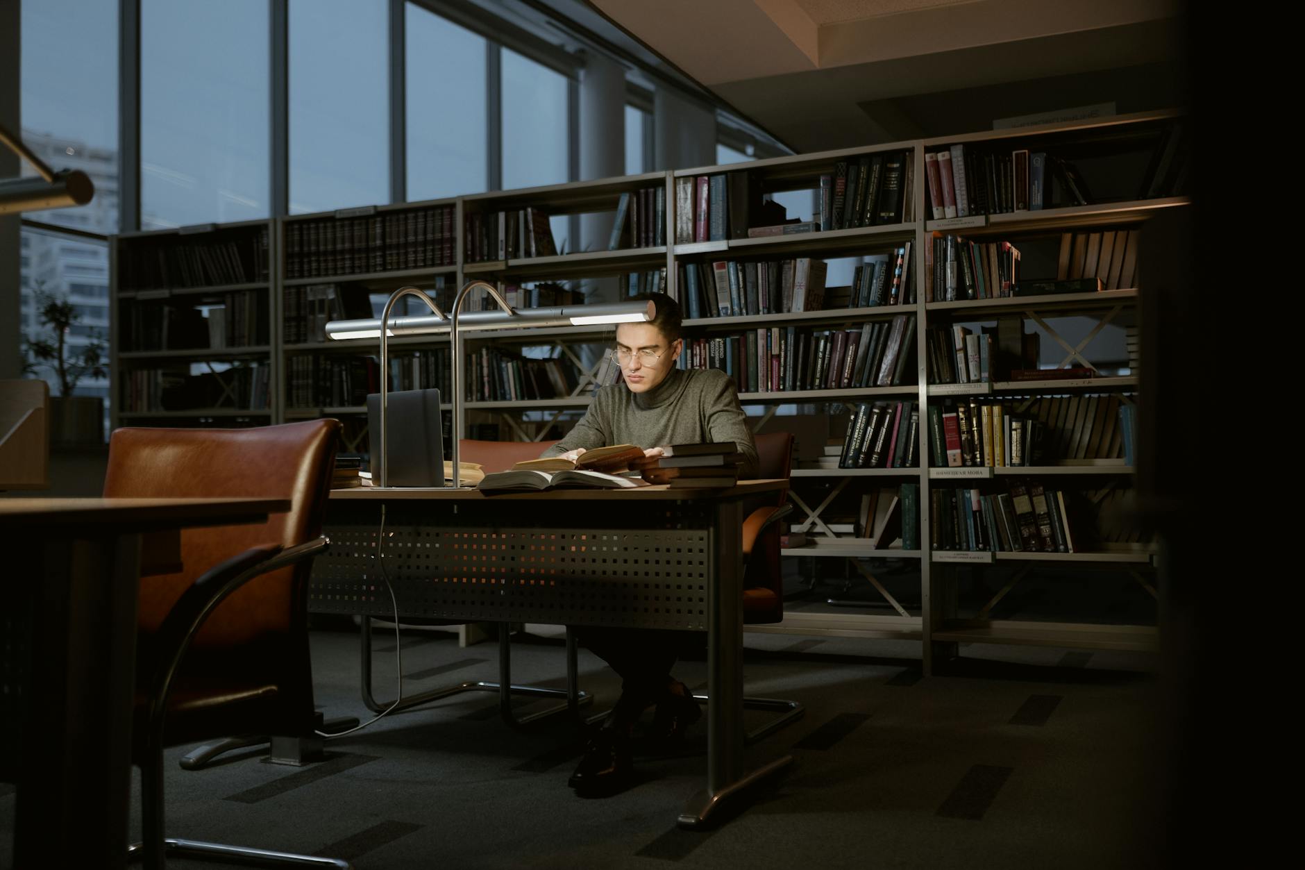 A man intensely studies in a quiet library, surrounded by books and soft lighting — UPI Study