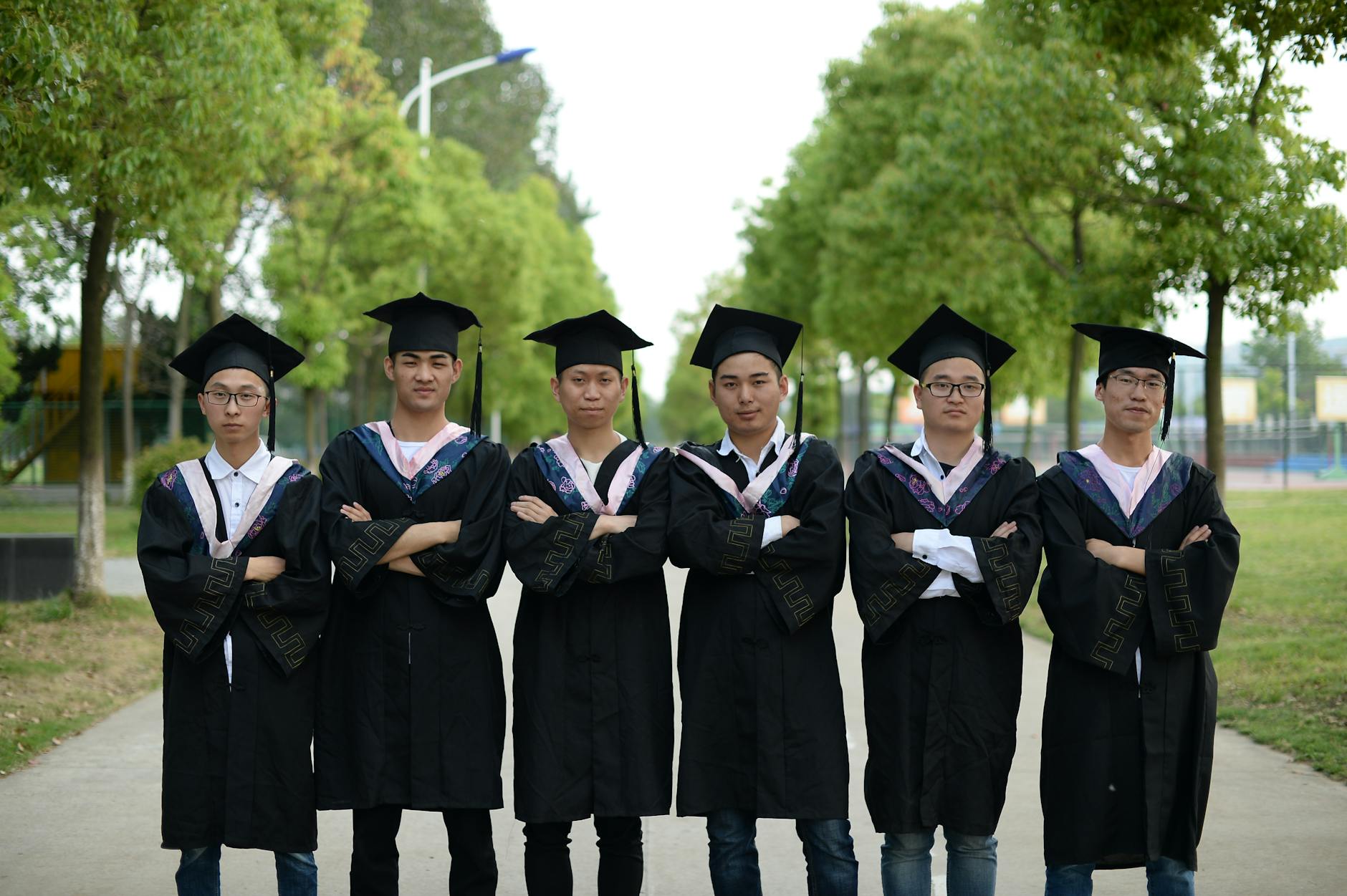 Group of young graduates in gowns and caps standing outdoors, celebrating academic achievement — UPI Study