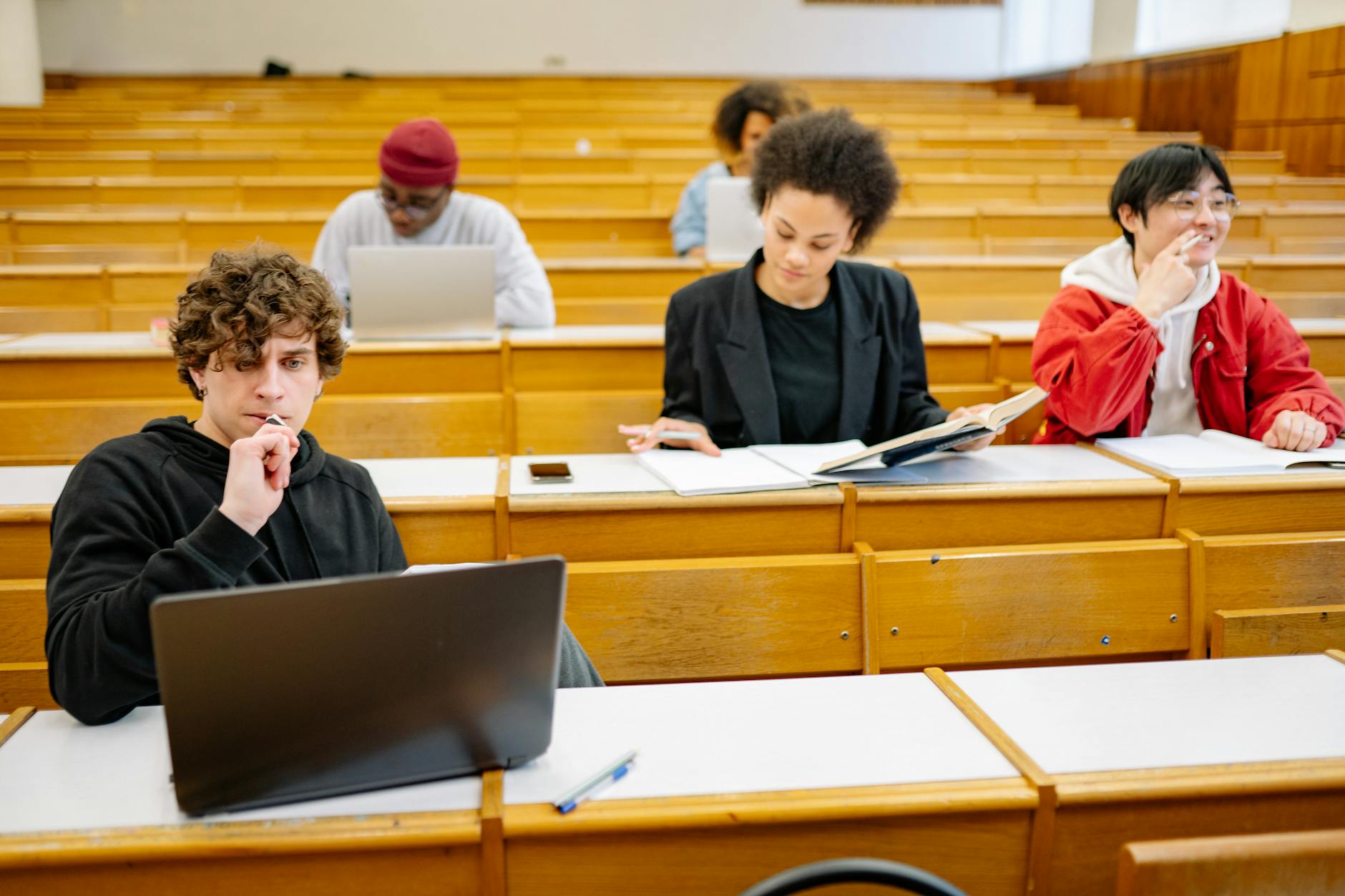 A diverse group of college students studying in a classroom setting with laptops and books — UPI Study