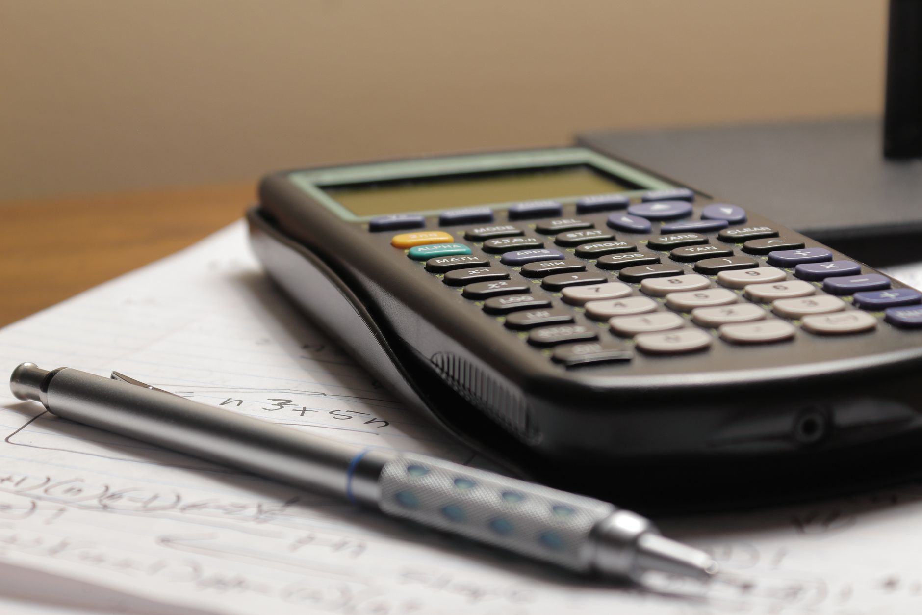 A detailed view of a calculator and pen resting on mathematical notes, ideal for educational and financial themes — UPI Study