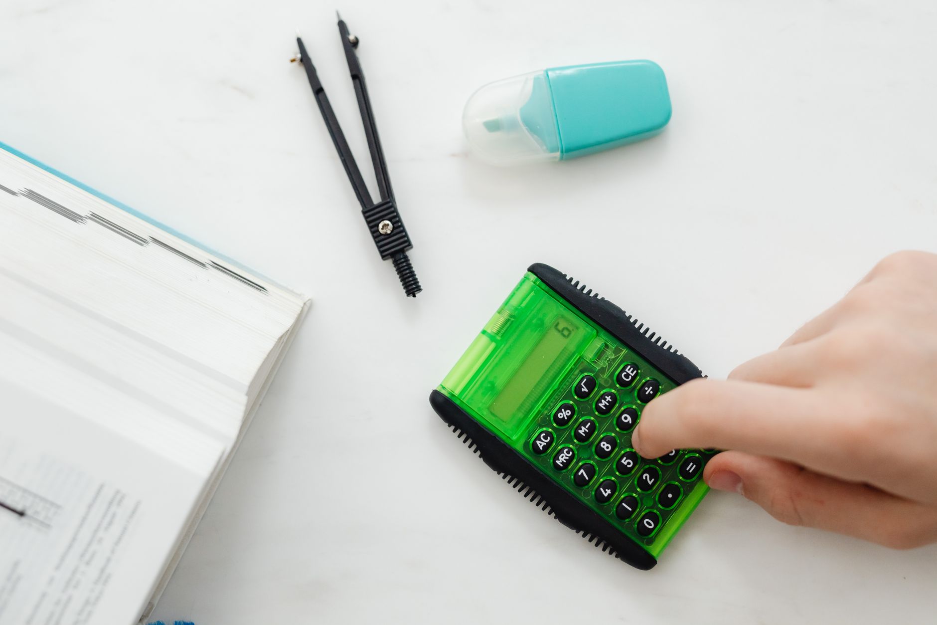 Close-up of a hand using a green calculator with stationery for studies or business calculations — UPI Study