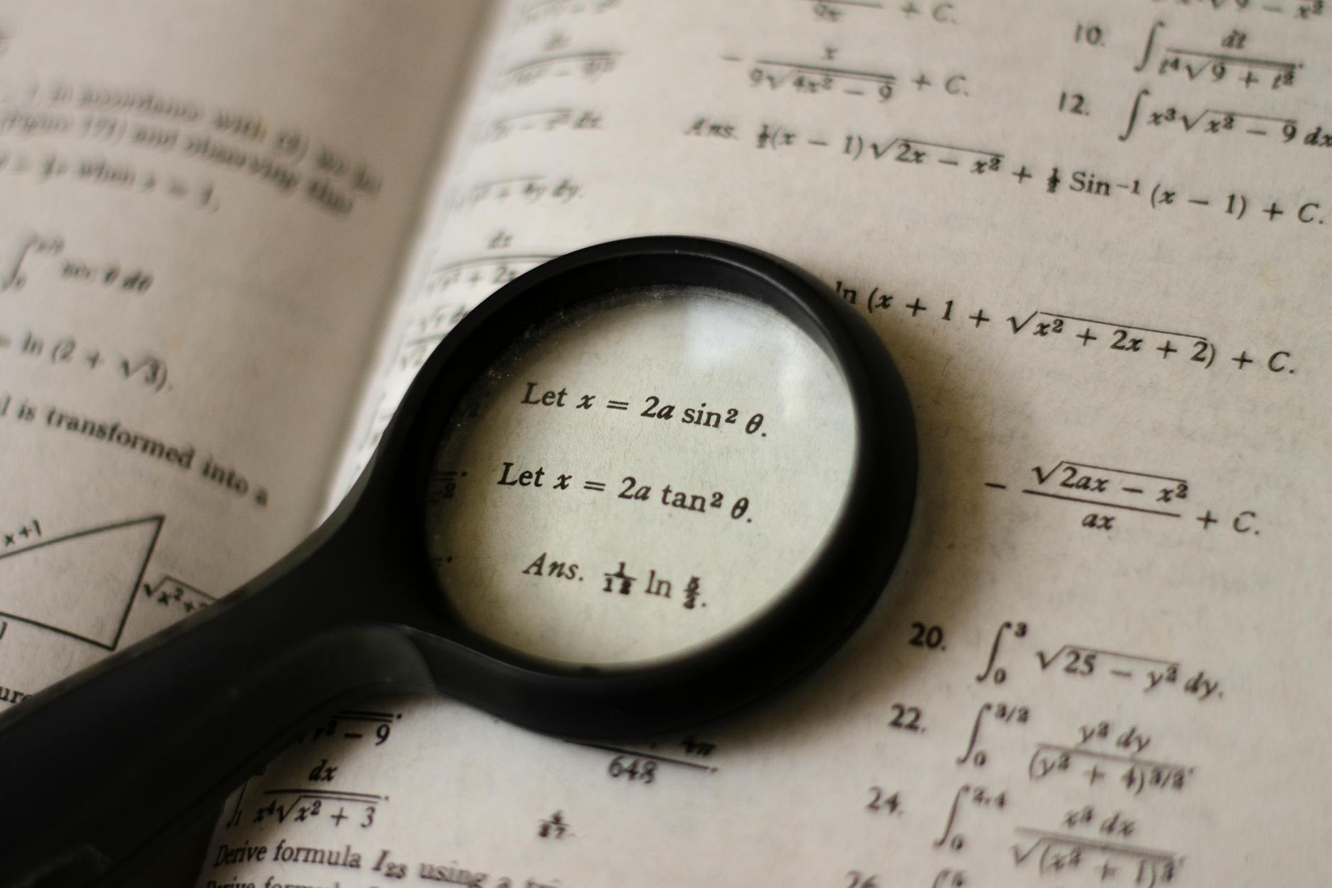 A magnifying glass focusing on mathematical equations in a textbook, symbolizing detailed study — UPI Study