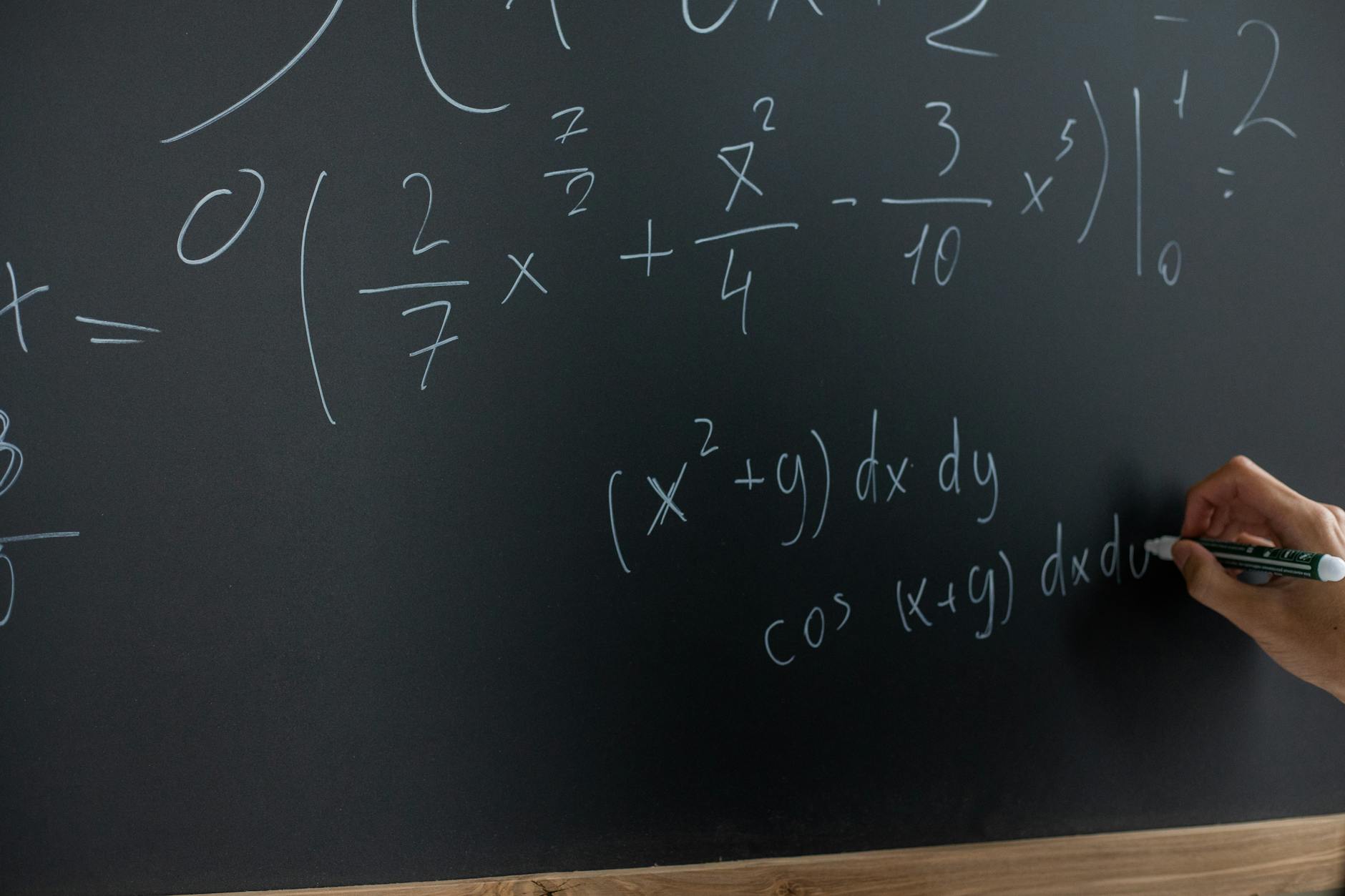 Hand writing mathematical equations on a chalkboard in a classroom setting — UPI Study
