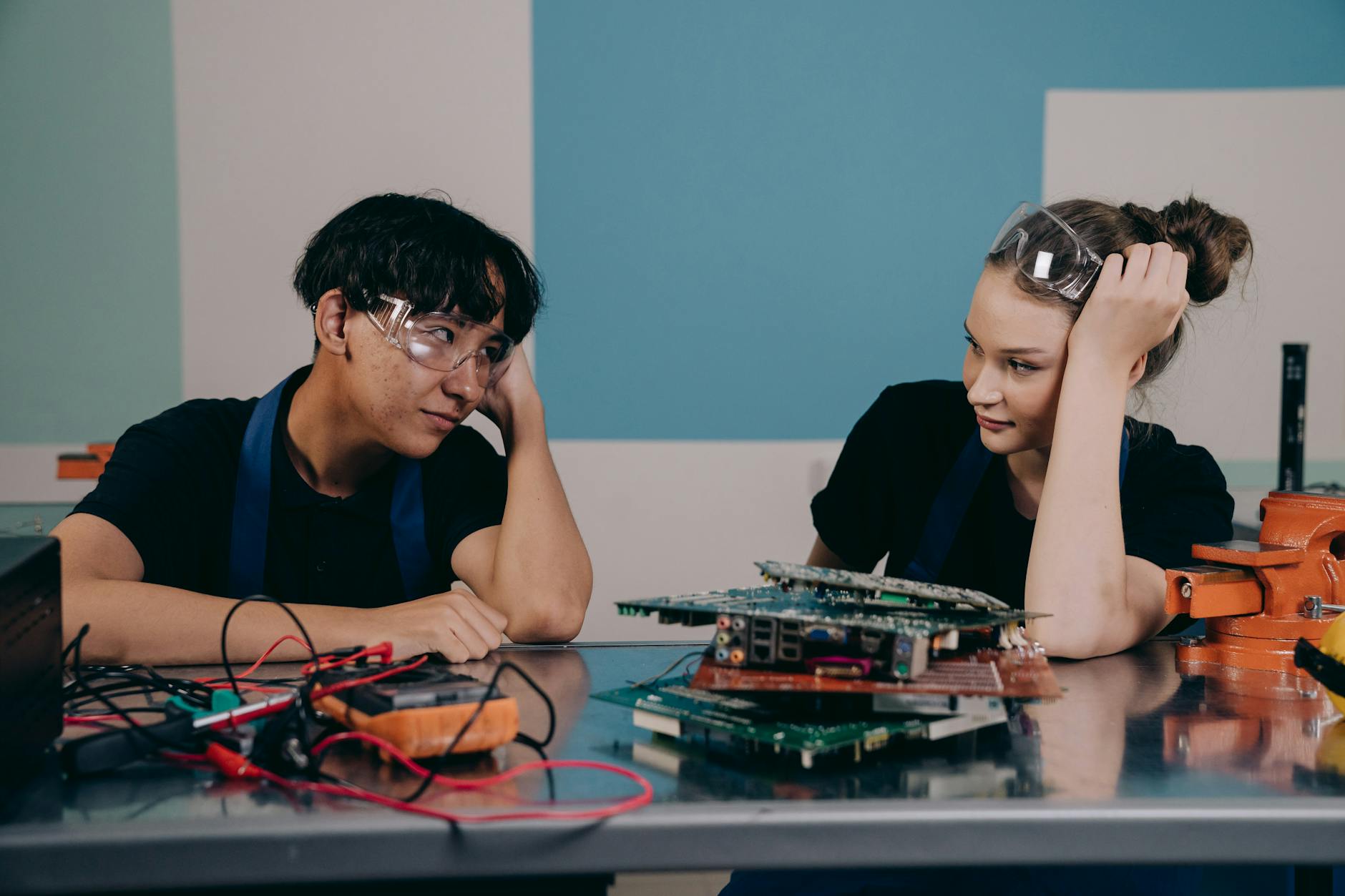 Two young engineers at a workbench, collaborating on electronics with circuit boards — UPI Study
